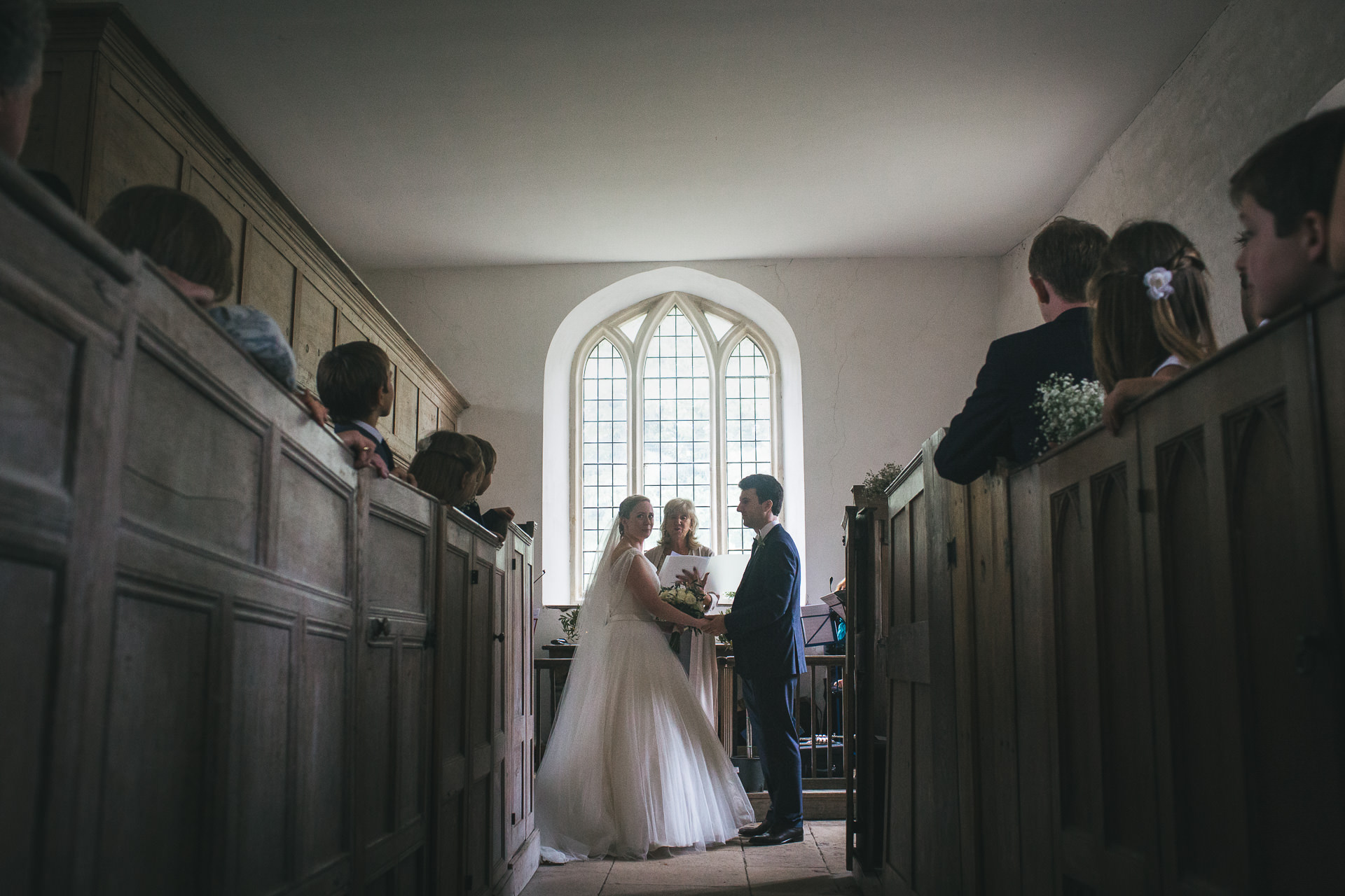 Bride and groom in front of large arched window during humanist wedding ceremony