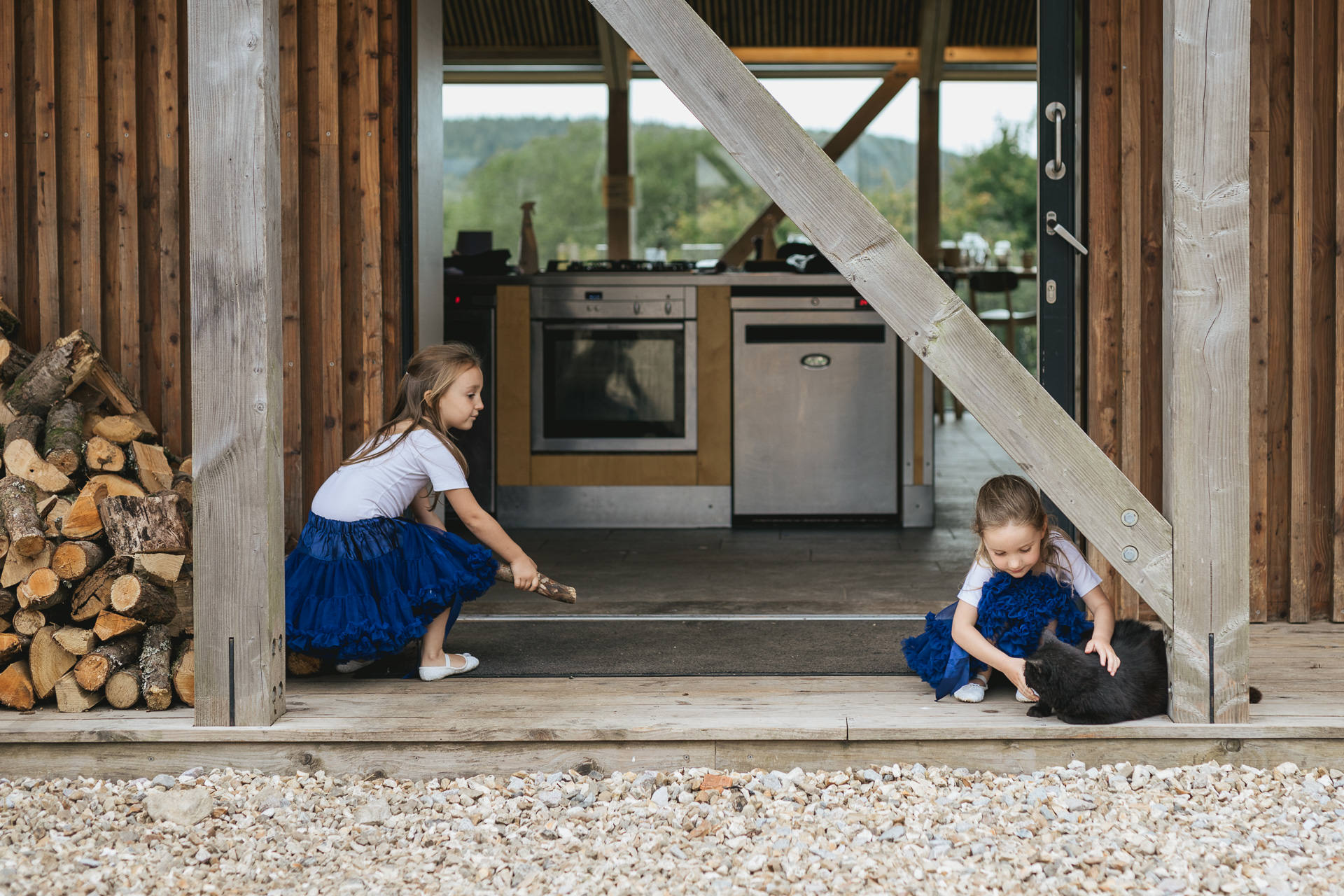 Flower girls in blue tutus playing with a black cat