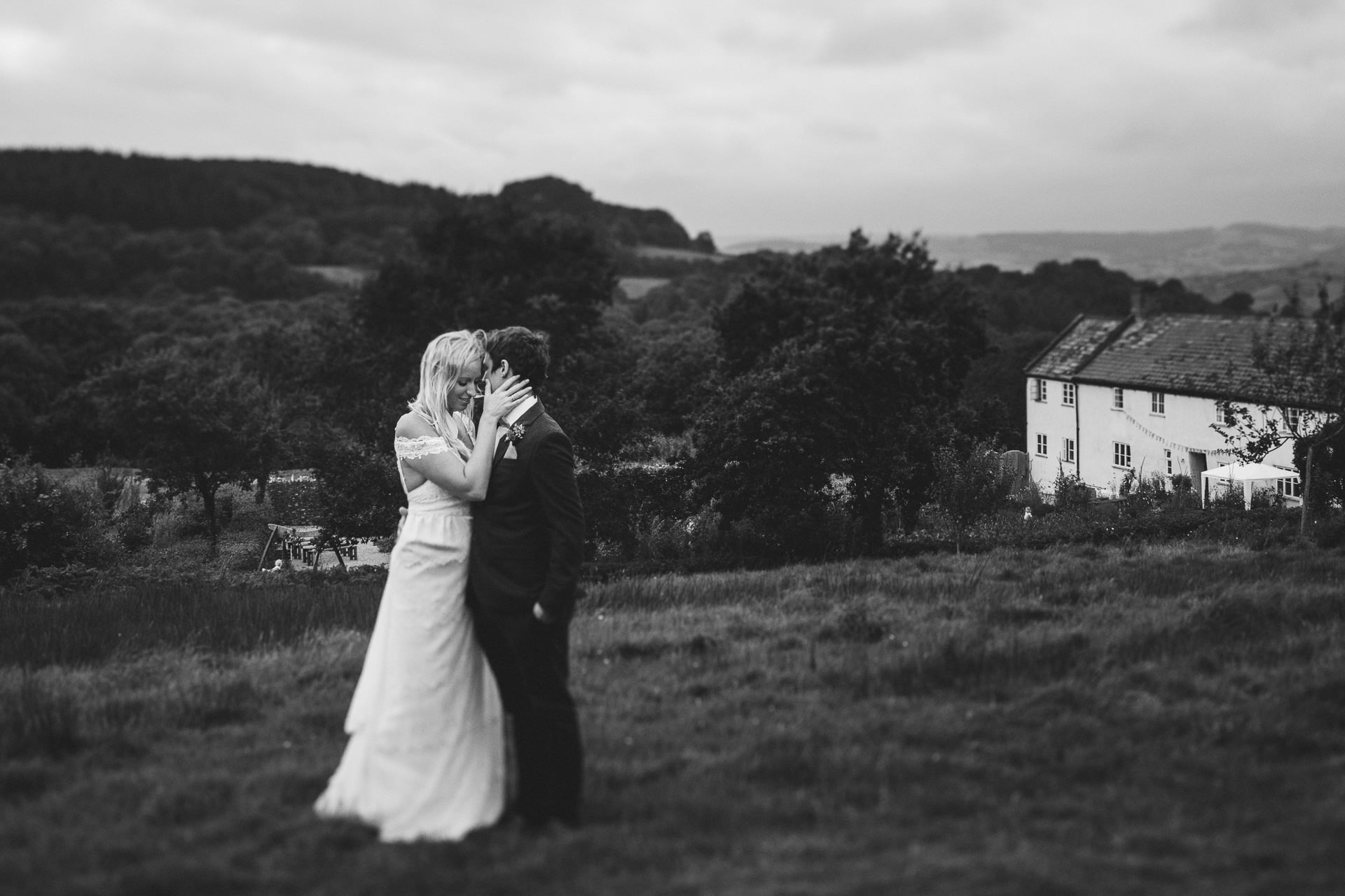 Bride and groom cuddling with River Cottage farmhouse in the background