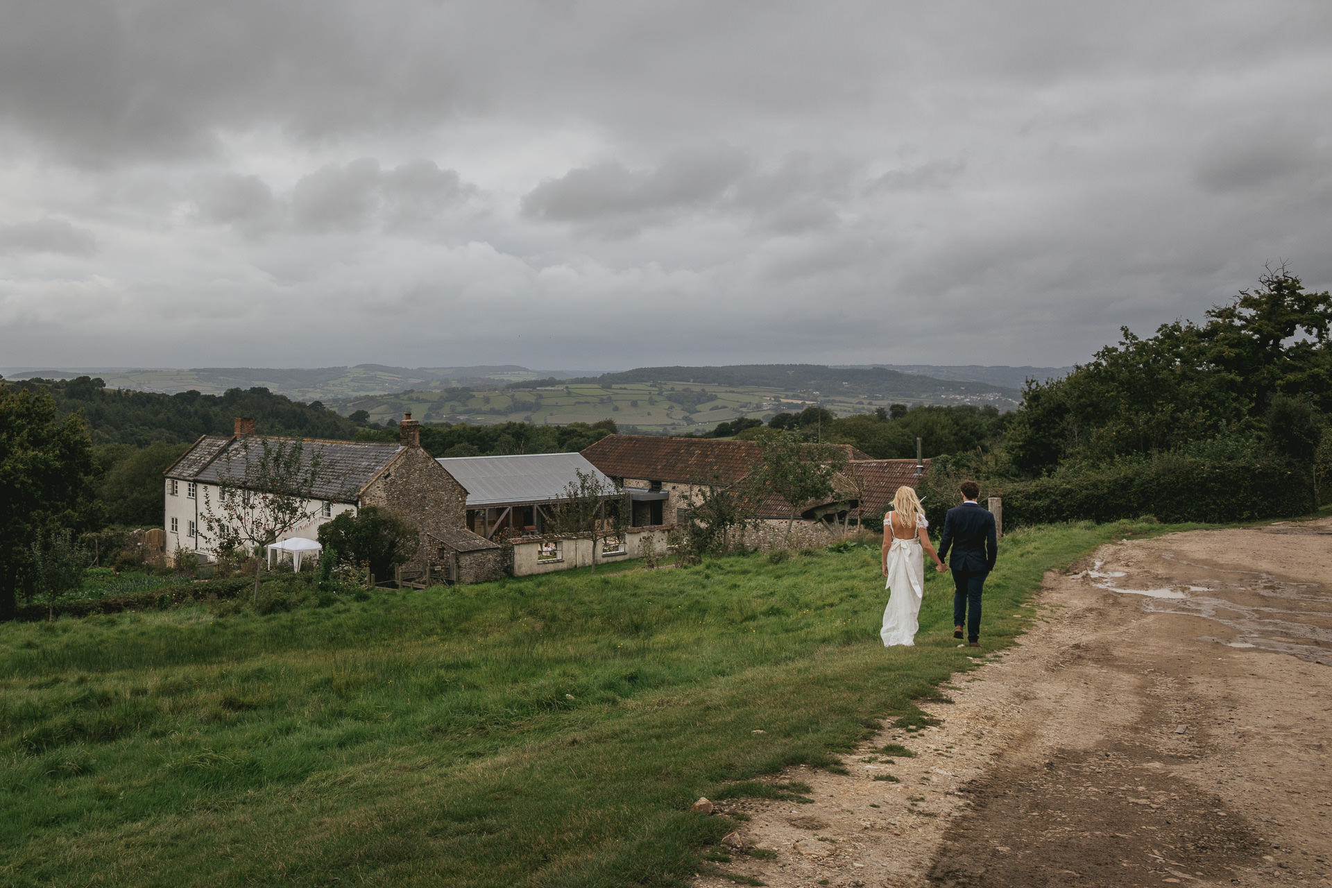 Bride and groom walk down the hill to River Cottage farmhouse