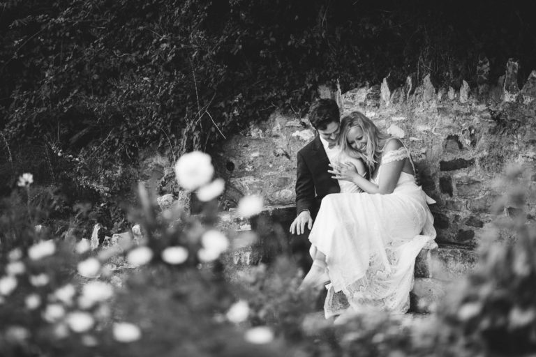 Bride and groom cuddling on a bench at river cottage