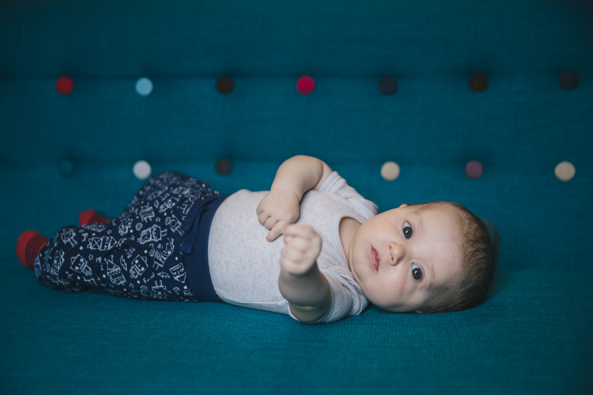 Relaxed family photos at home of a small baby on a stylish blue sofa