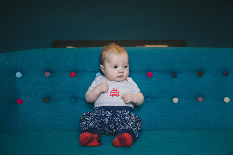 A small baby boy on a blue sofa with coloured buttons