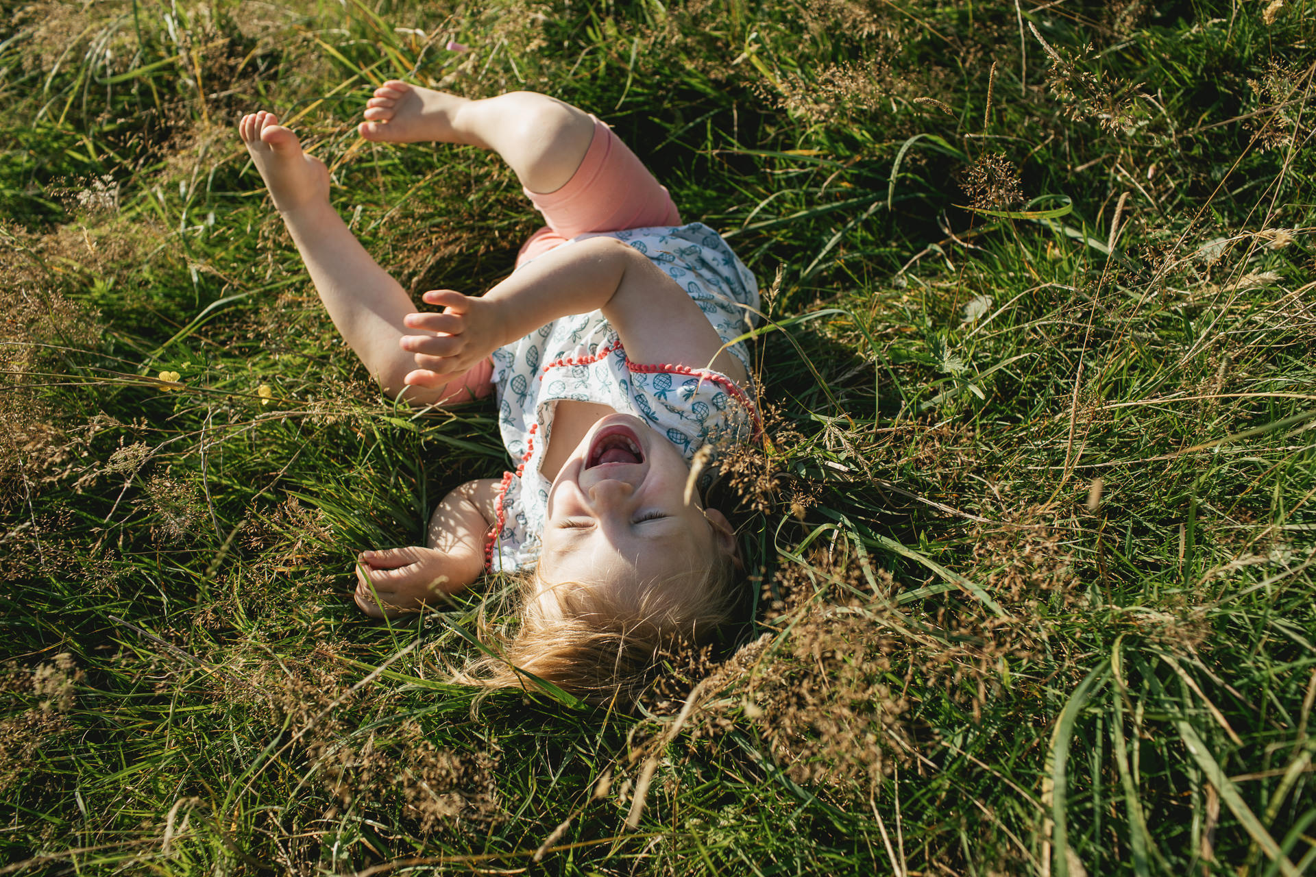 A young girl rolling in the grass and laughing