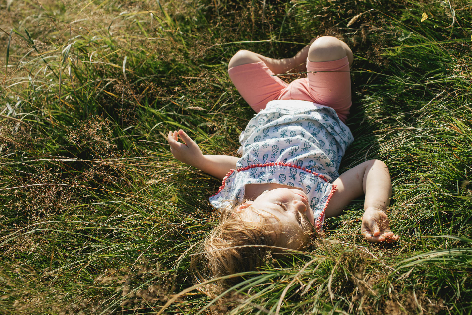 A young girl rolling in long grass