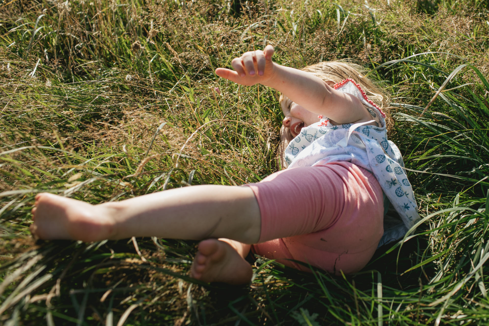 Toddler rolling around in long grass