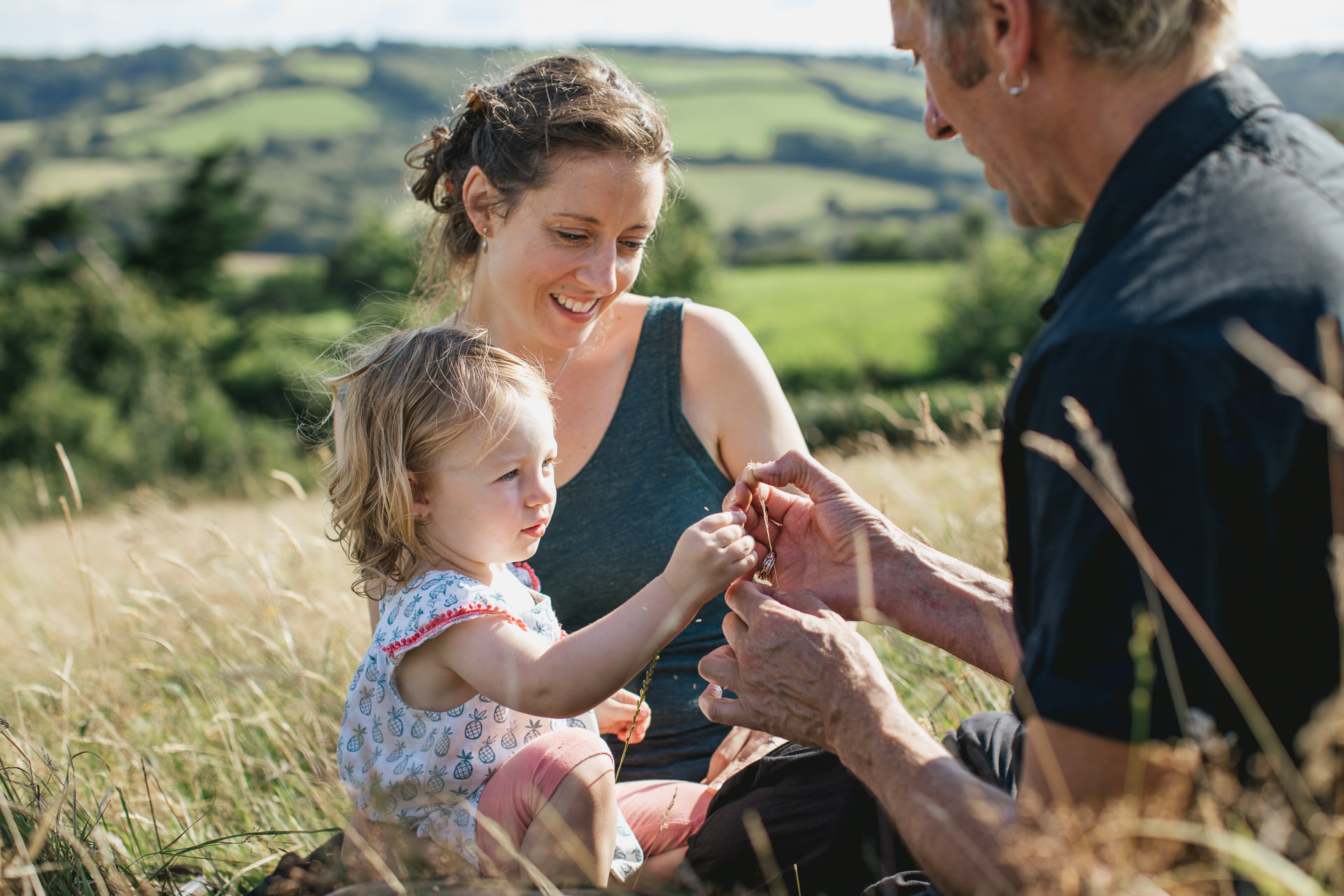 Two parents with a young daughter talking together in a field