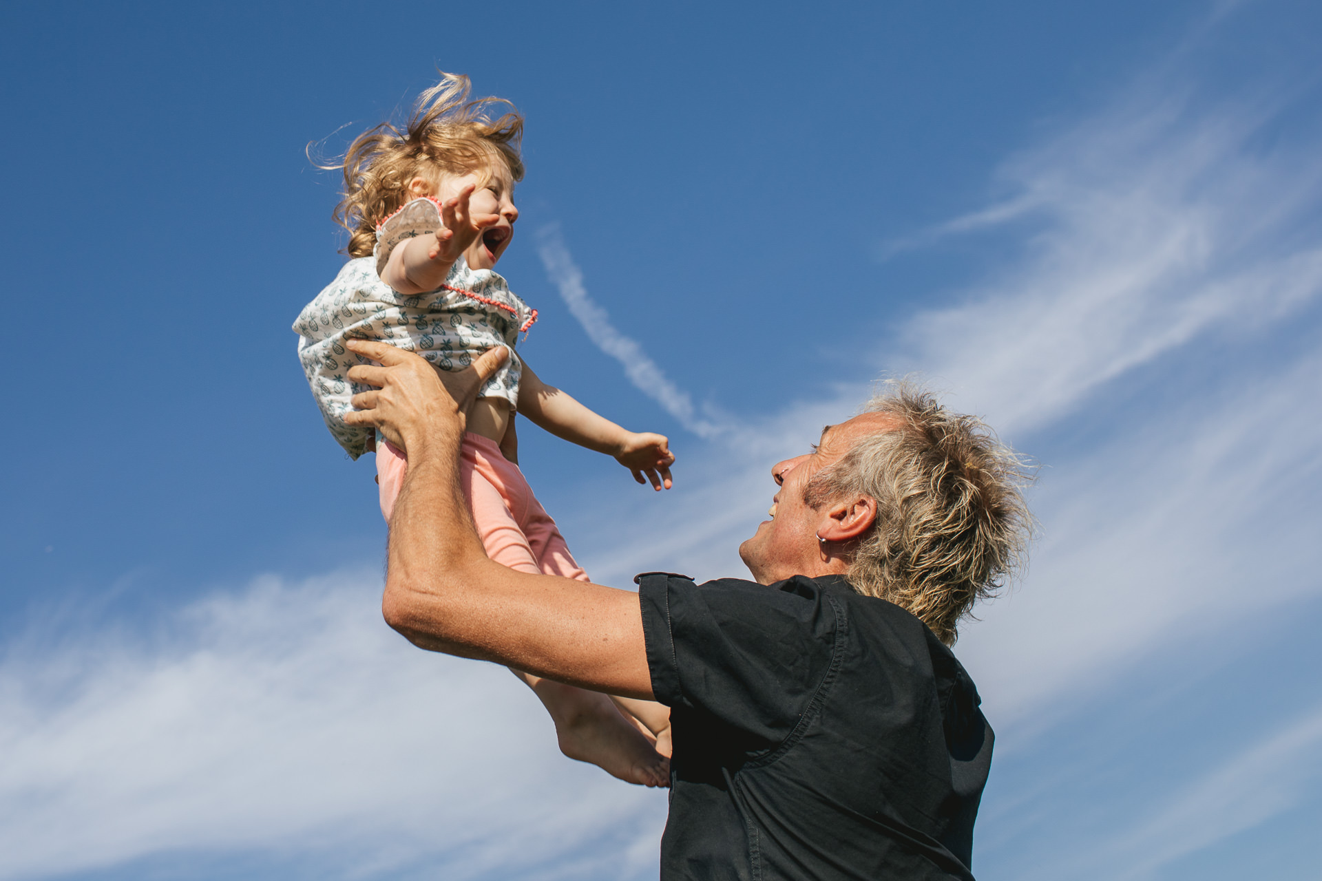 A dad throwing his small daughter up in the air