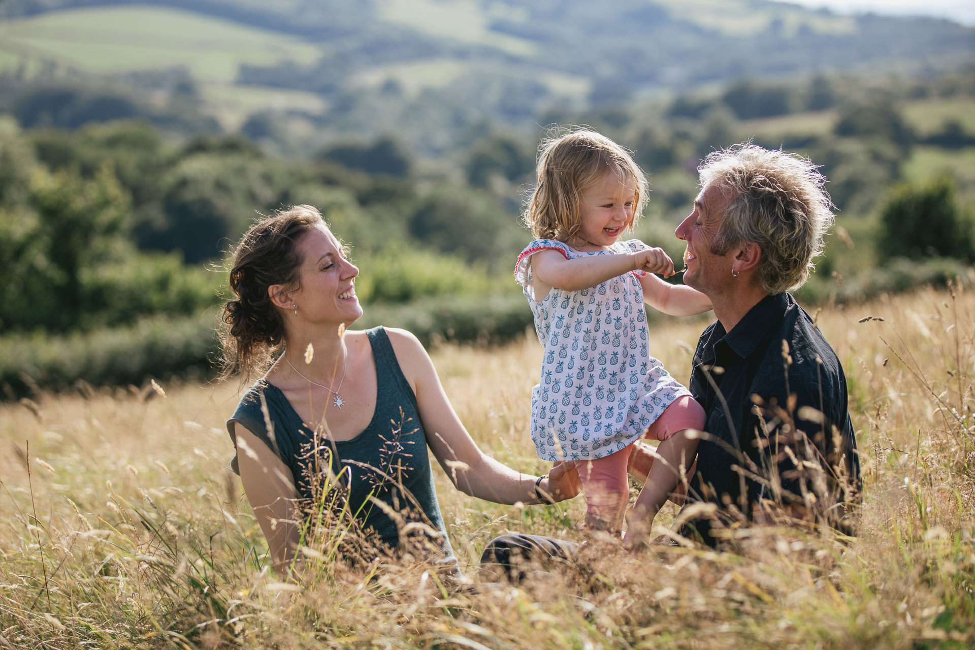 Two parents with a young daughter in a field