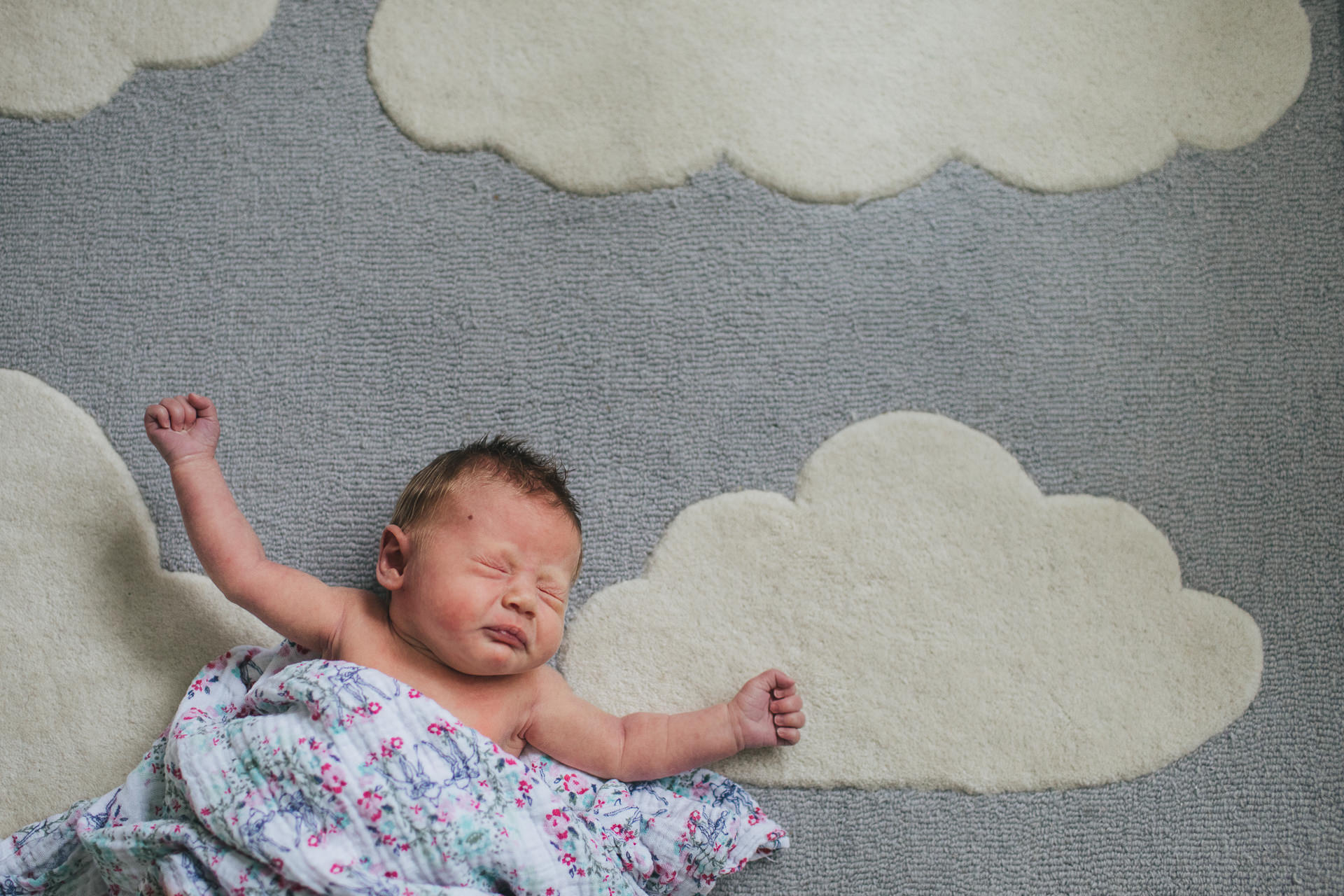 A newborn baby, sneezing on a rug of clouds