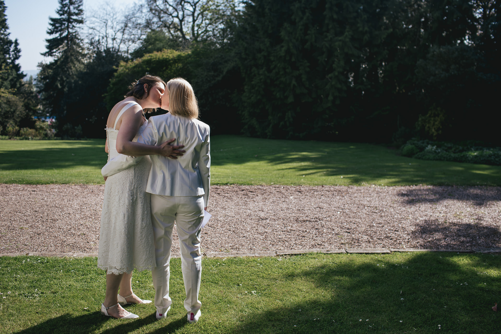 Two brides kissing on a grass lawn