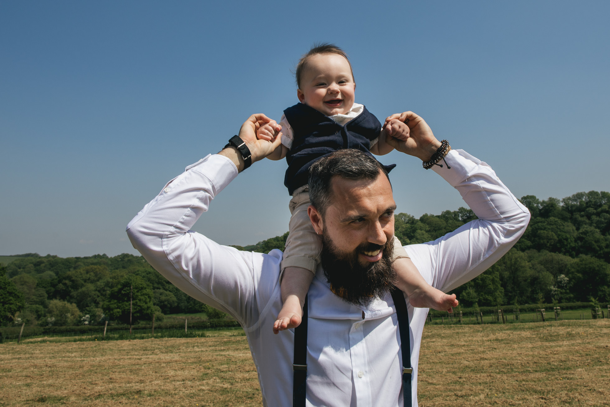 Groom with laughing baby on his shoulders