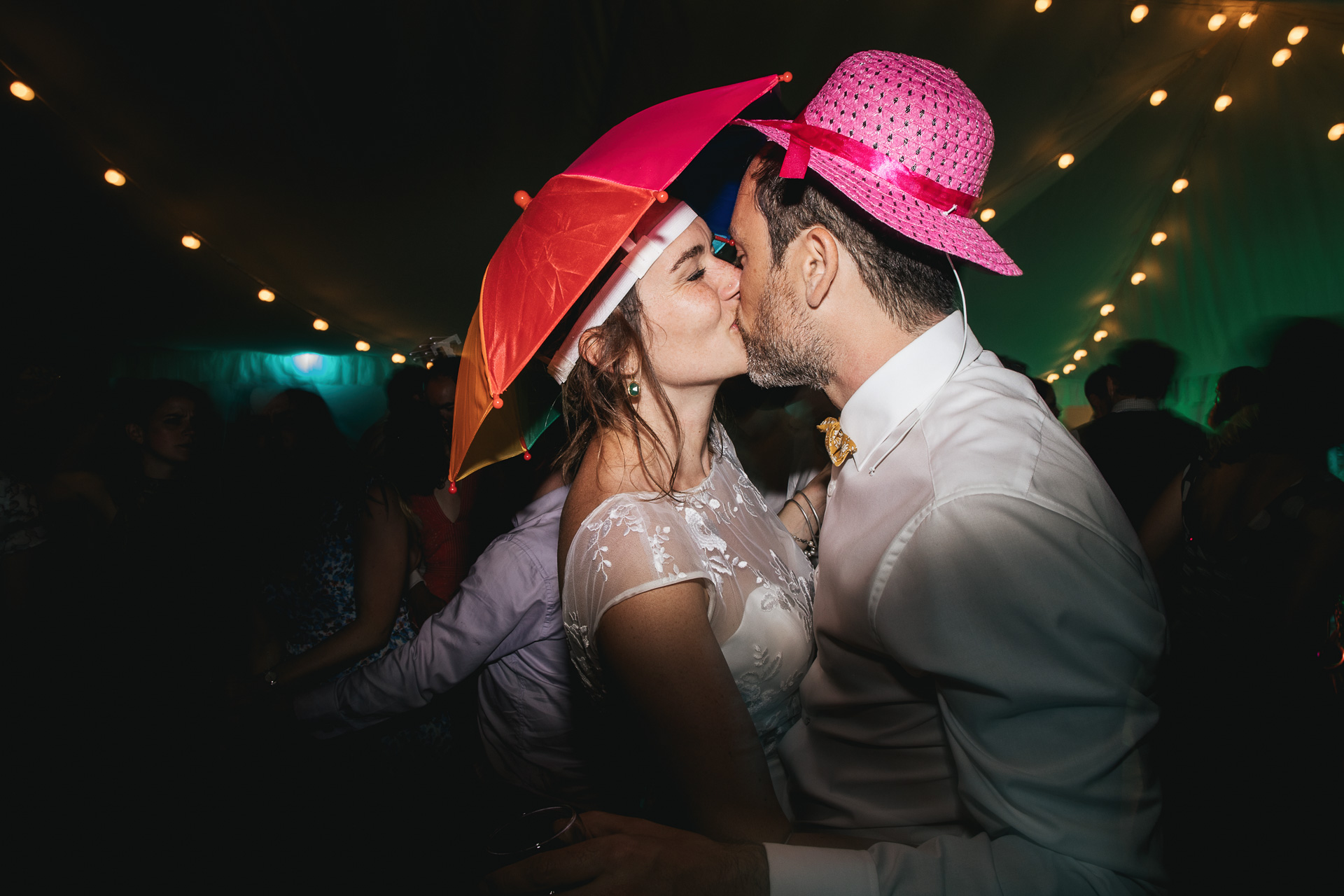 Bride and groom kissing on dance floor in silly hats