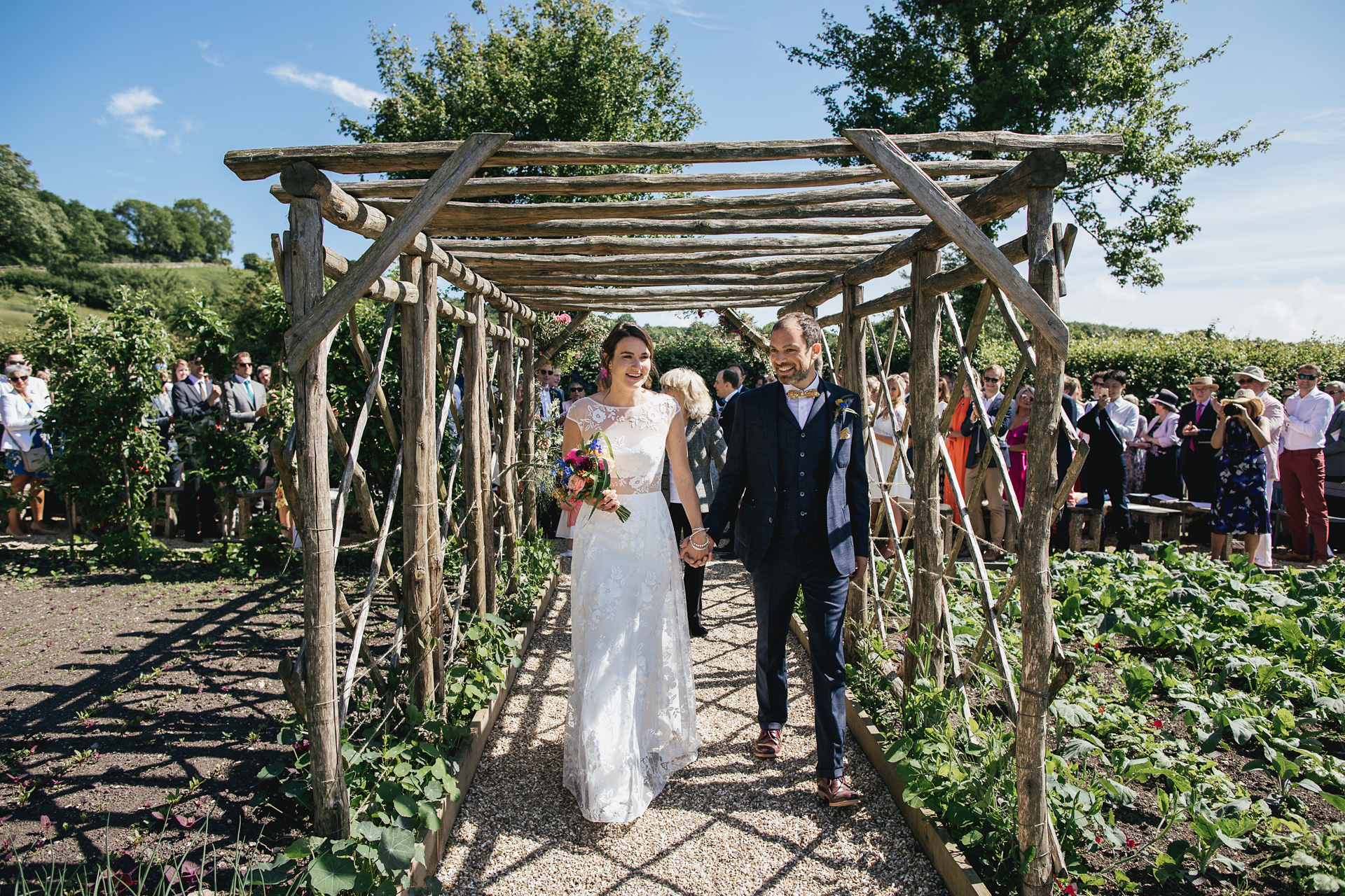 Bride and groom walking down the aisle in kitchen garden