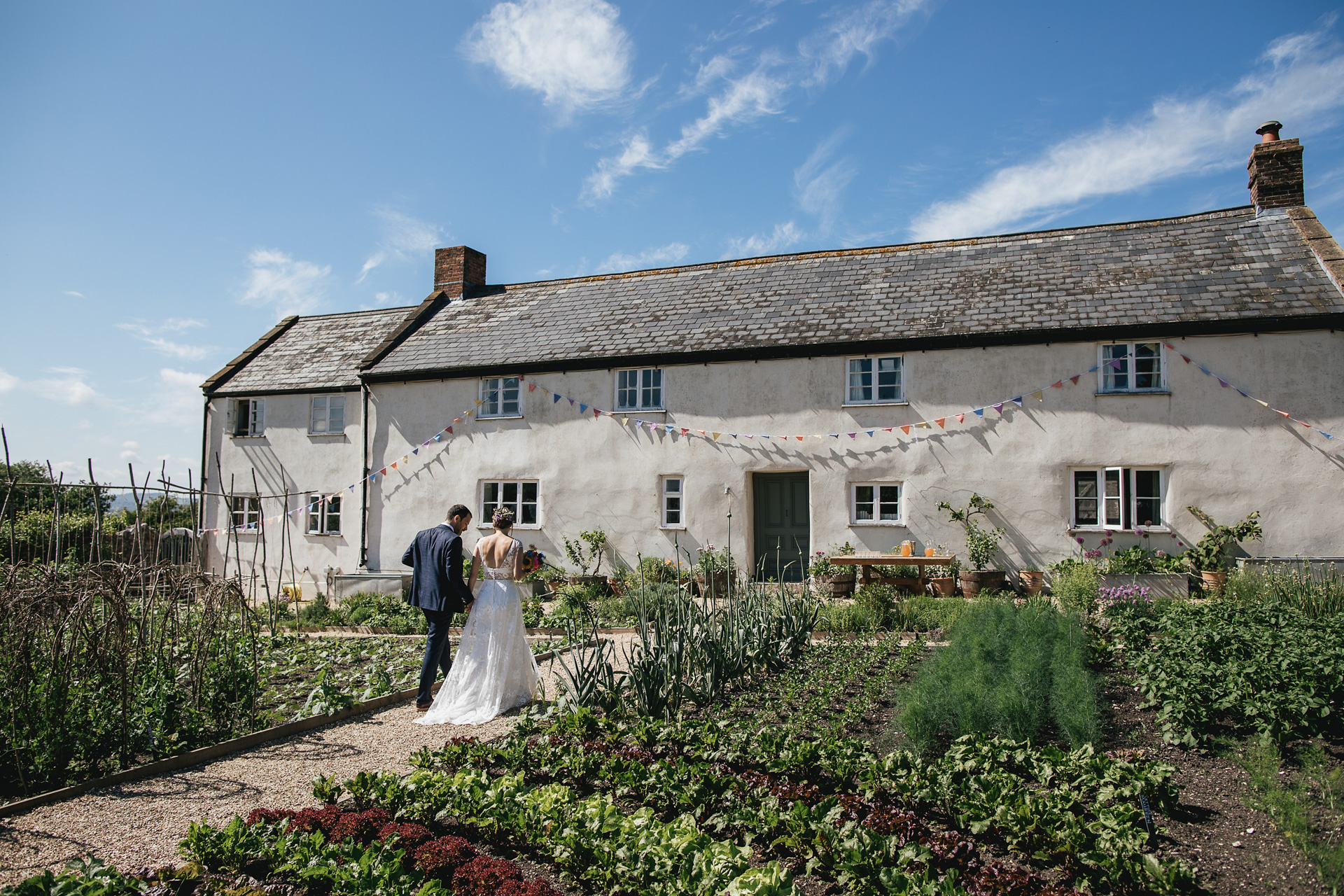 Bride and groom walk towards River Cottage farmhouse
