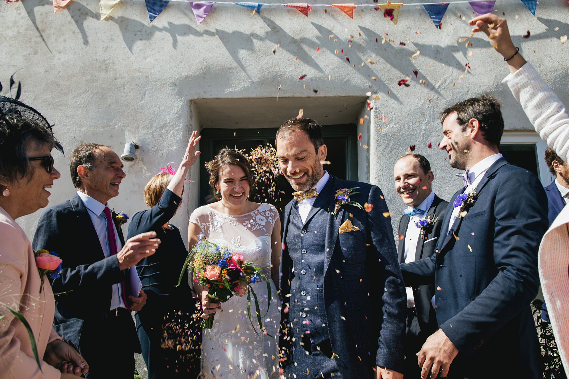 Bride and groom with guests throwing confetti