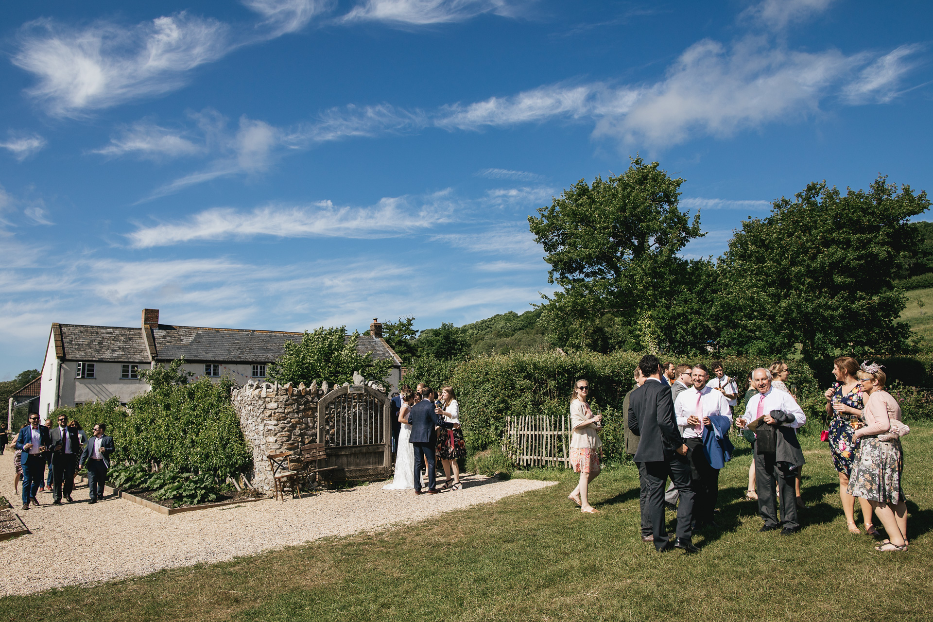 Wedding guests in field with River Cottage farmhouse behind