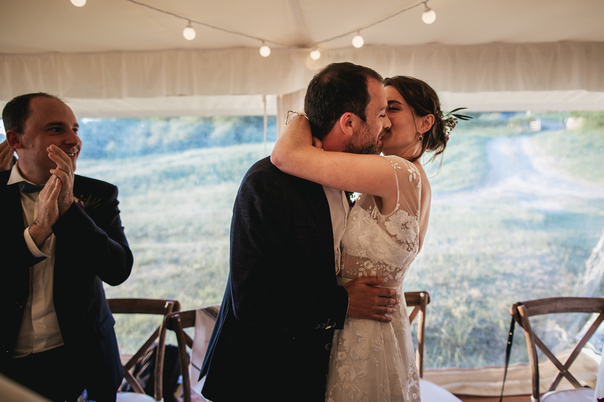 Bride kissing groom in marquee