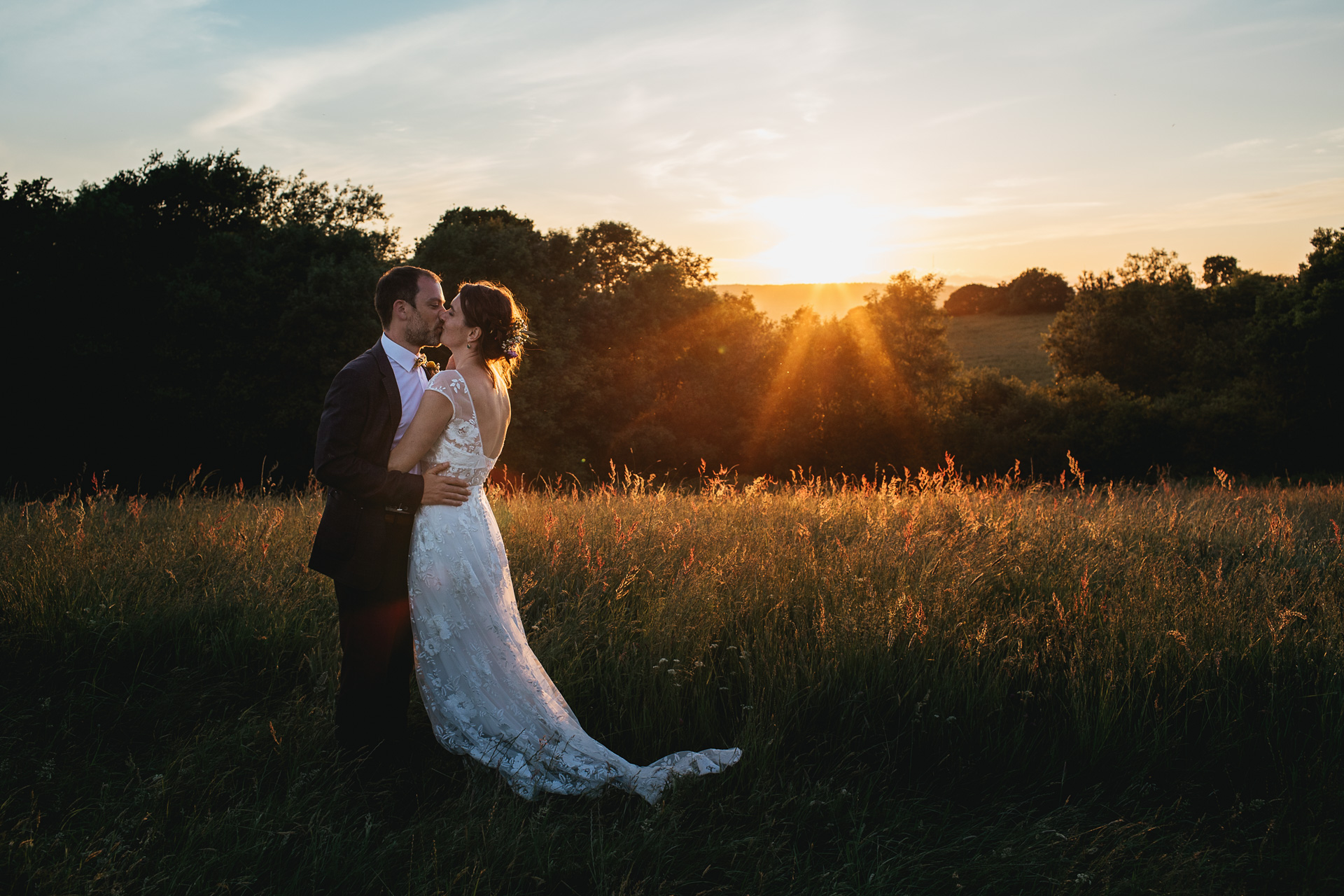 Bride and groom kissing with a sunset