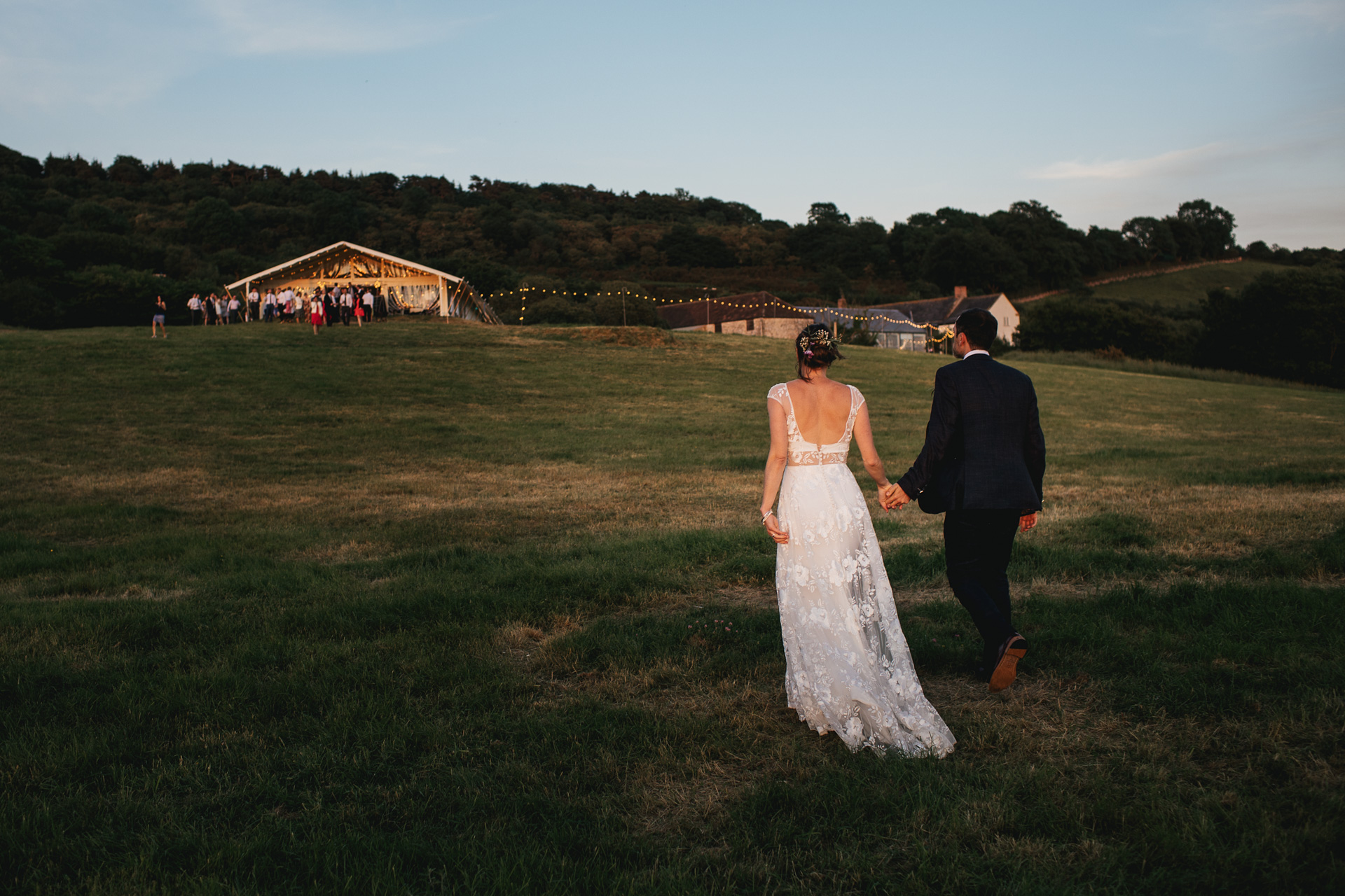 Bride and groom walking across a field 