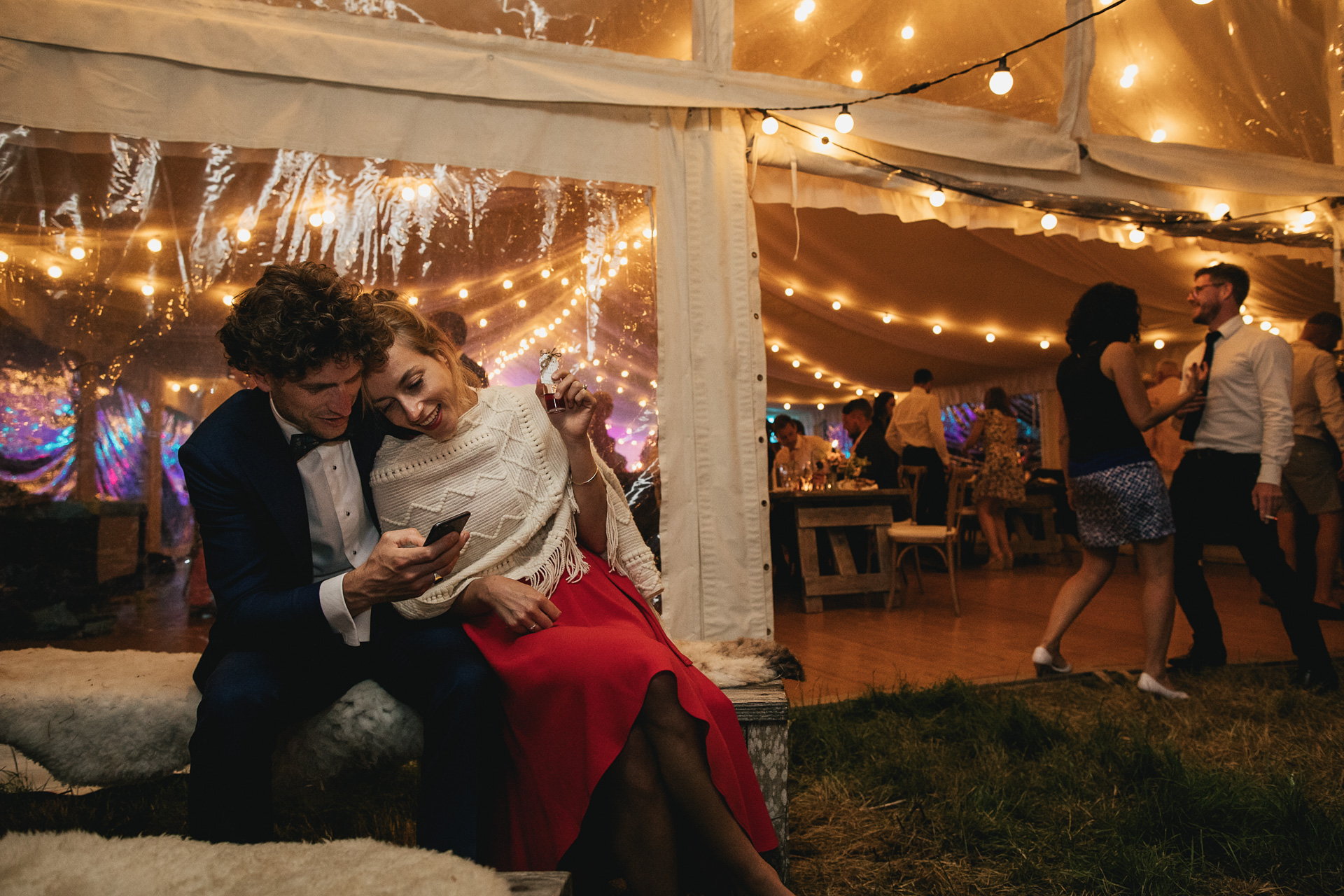 Two wedding guests sitting outside a marquee