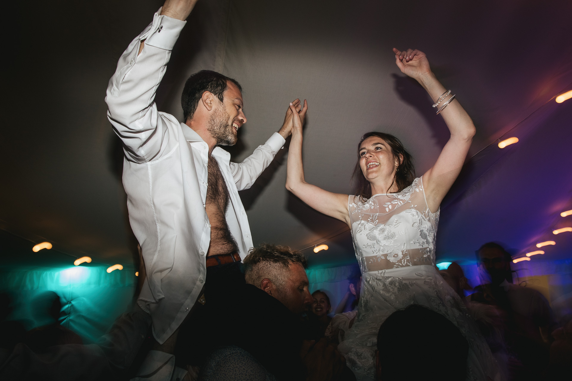 Bride and groom dancing on guests shoulders