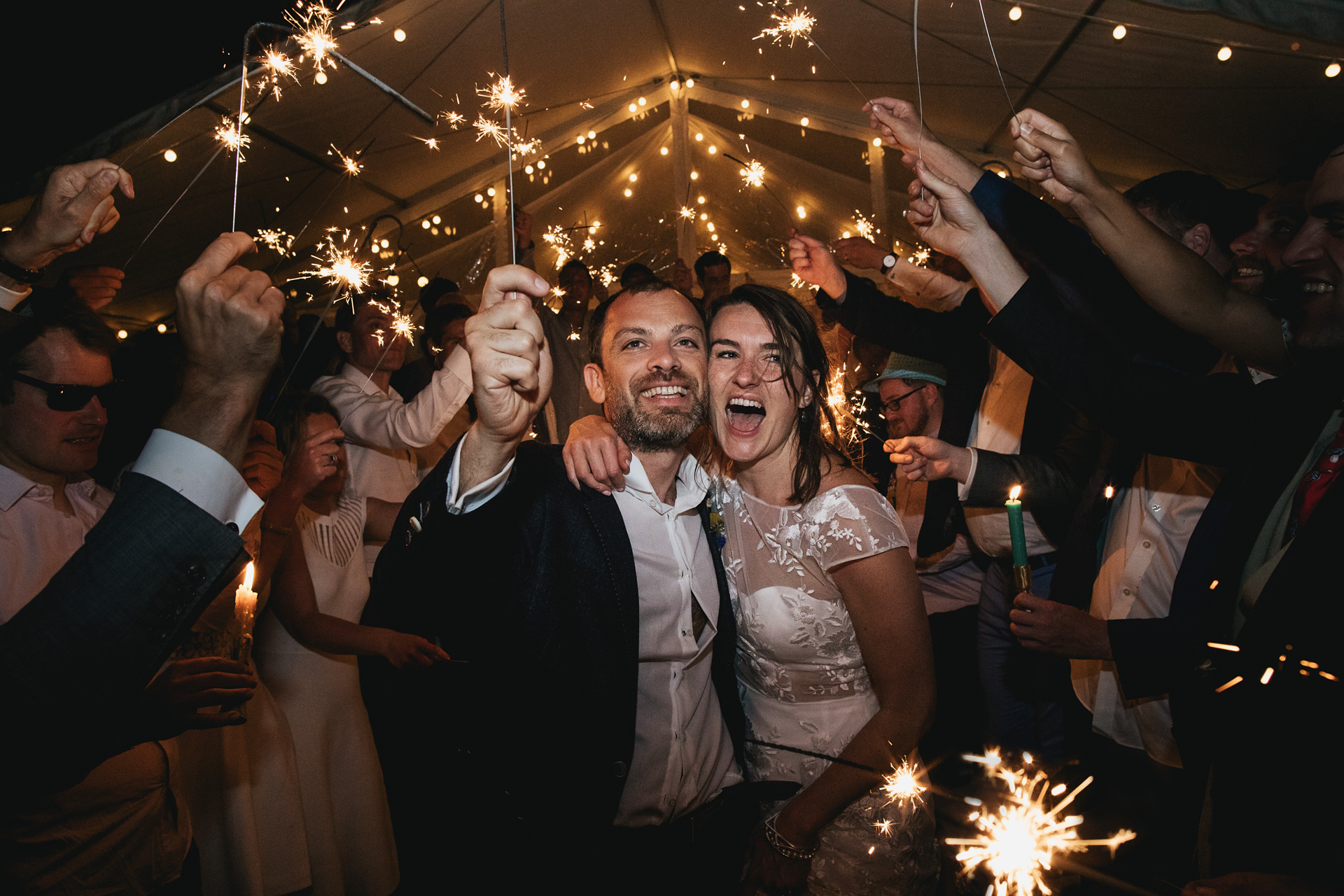 Bride and groom laughing surrounded by sparklers