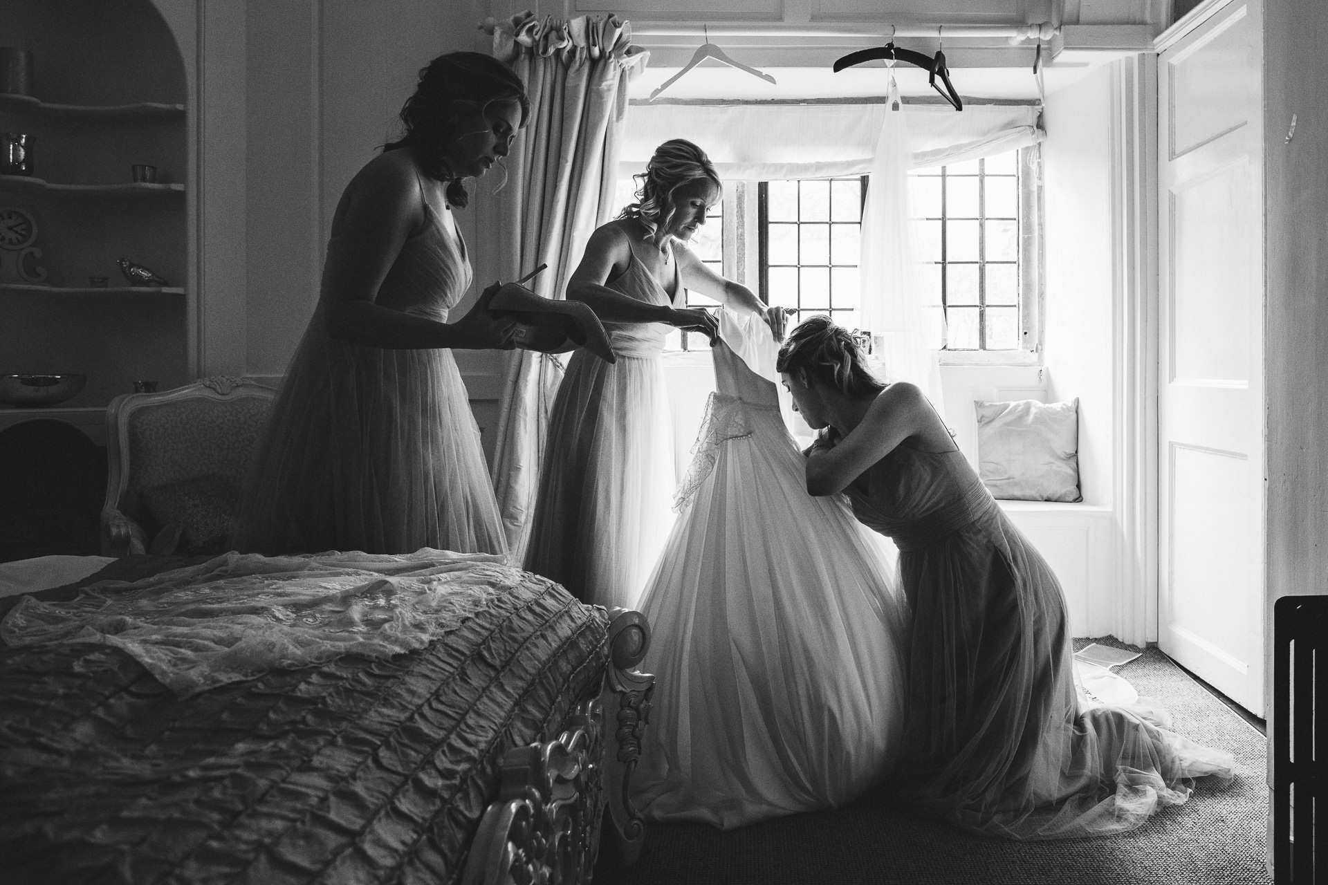 Bridesmaids preparing wedding dress for bride