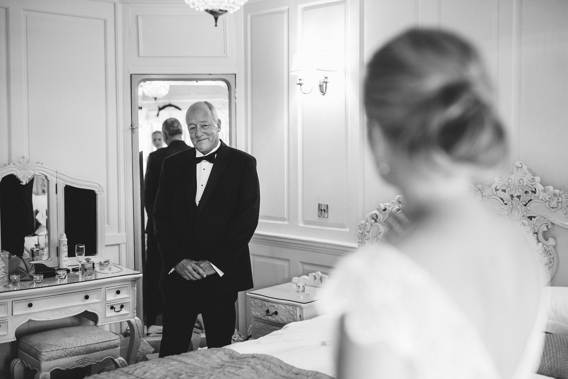 Father looking at daughter in wedding dress and smiling
