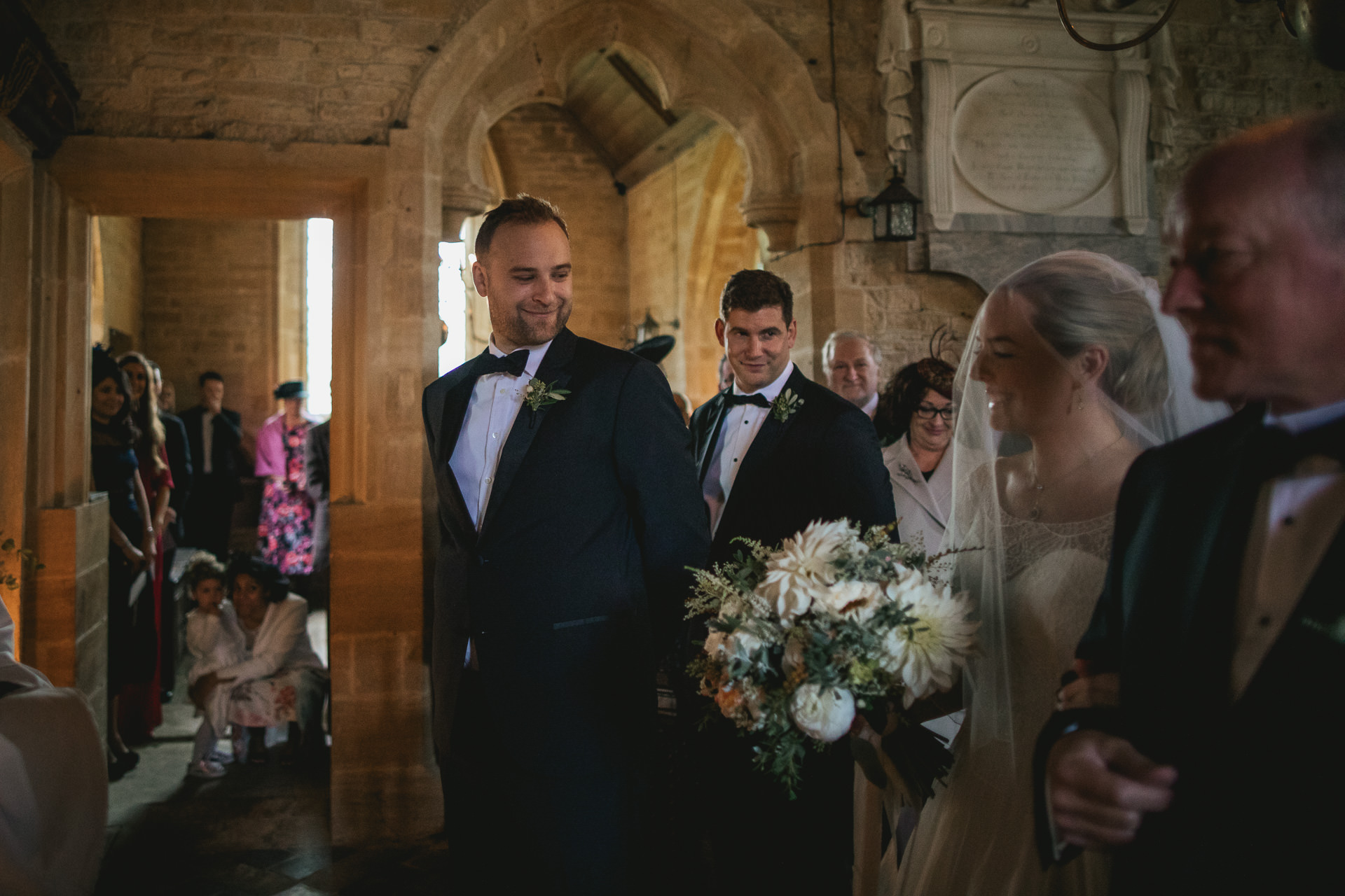 Groom smiling at bride at the front of the church