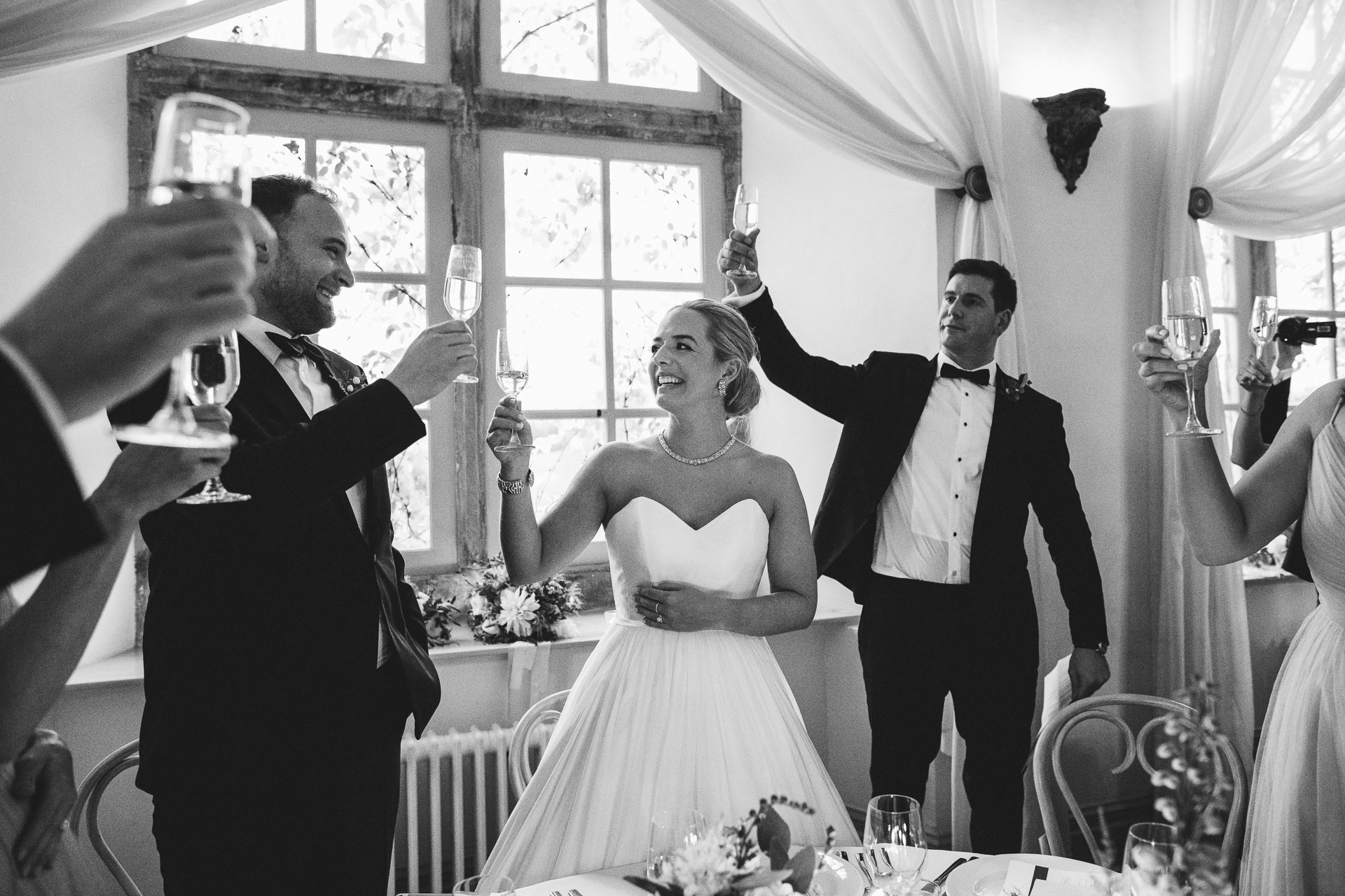 Bride and groom raising glasses and smiling at each other