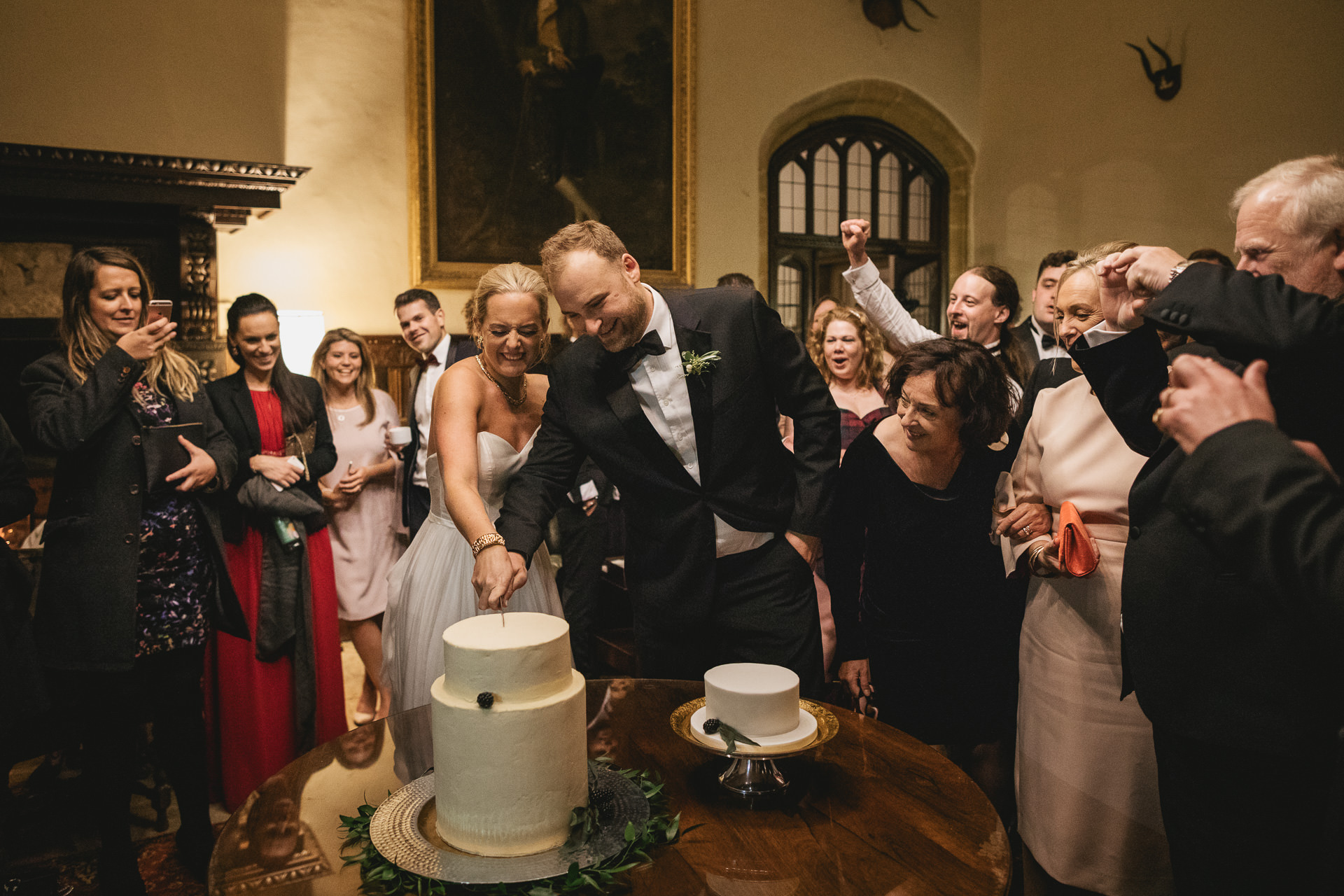 Bride and groom cutting cake in the entrance hall of Brympton House