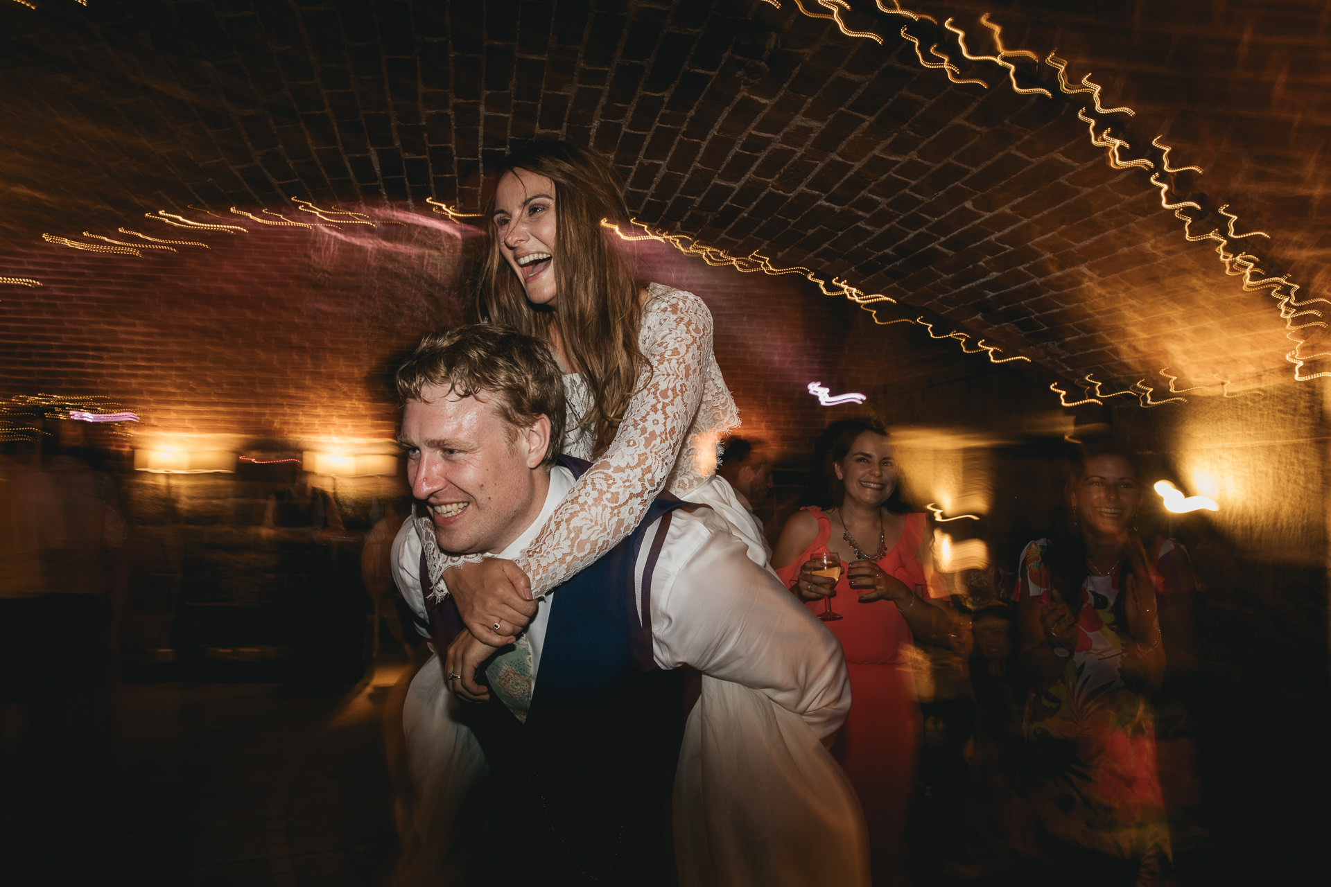 Groom giving bride a piggy back on the dance floor