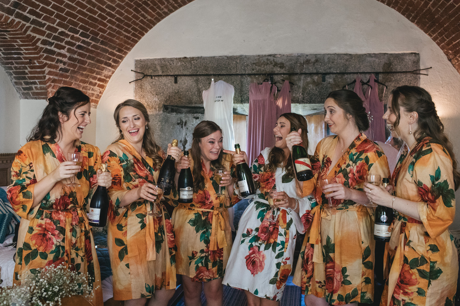 Bride and bridesmaids laughing with champagne