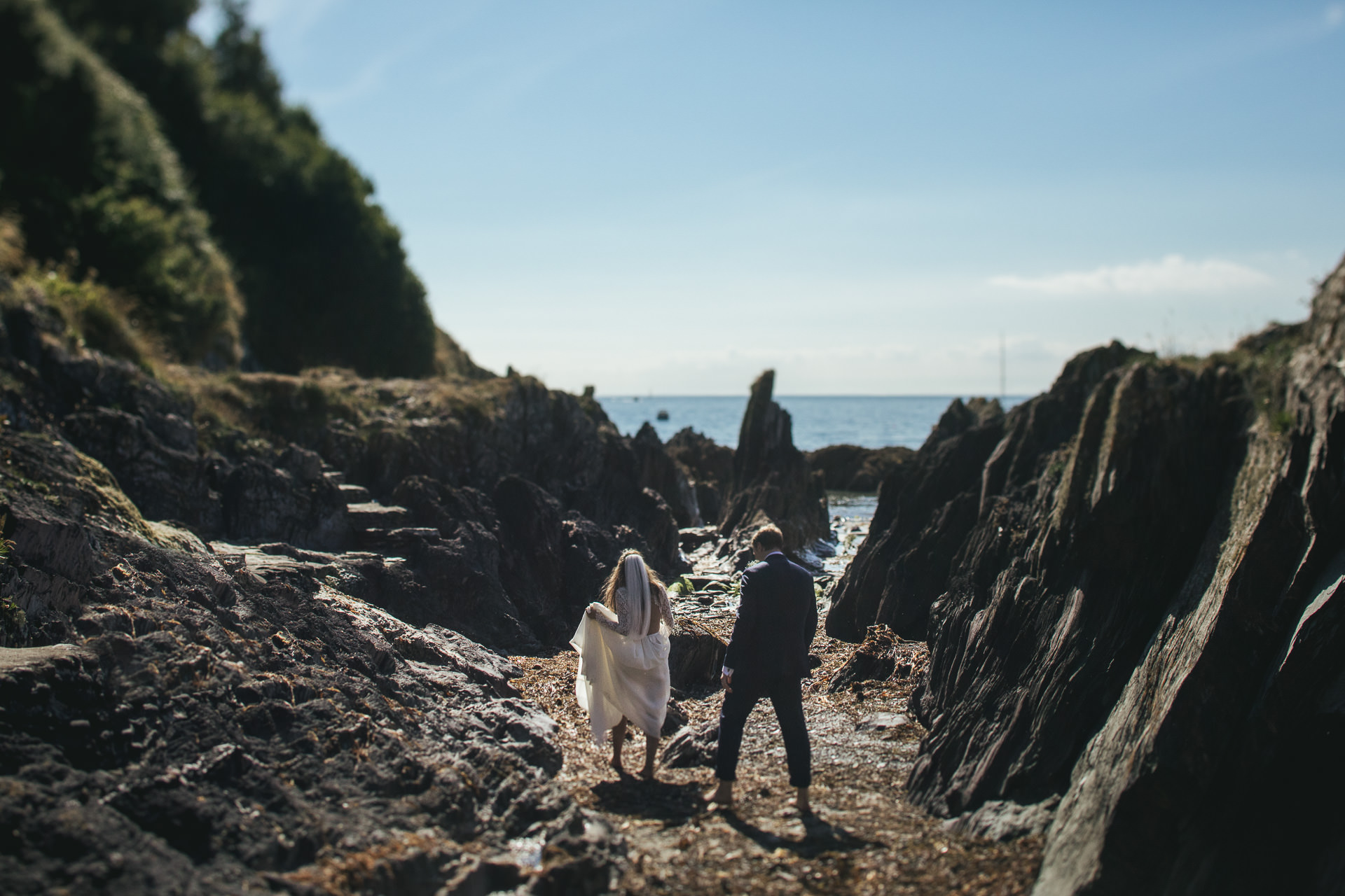 Bride and groom walking through rocks on the beach