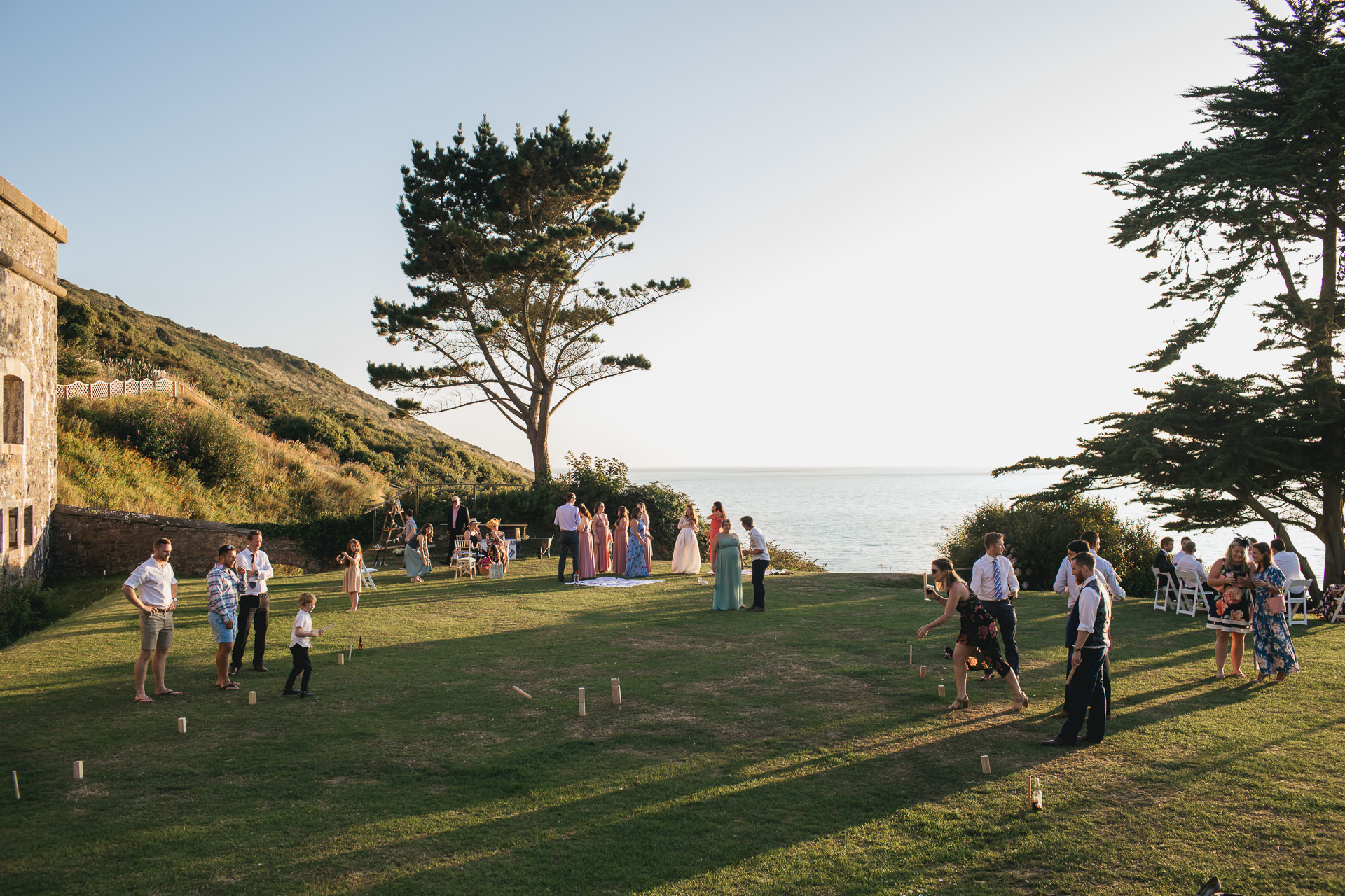 Wedding guests in the evening sunlight with the sea behind