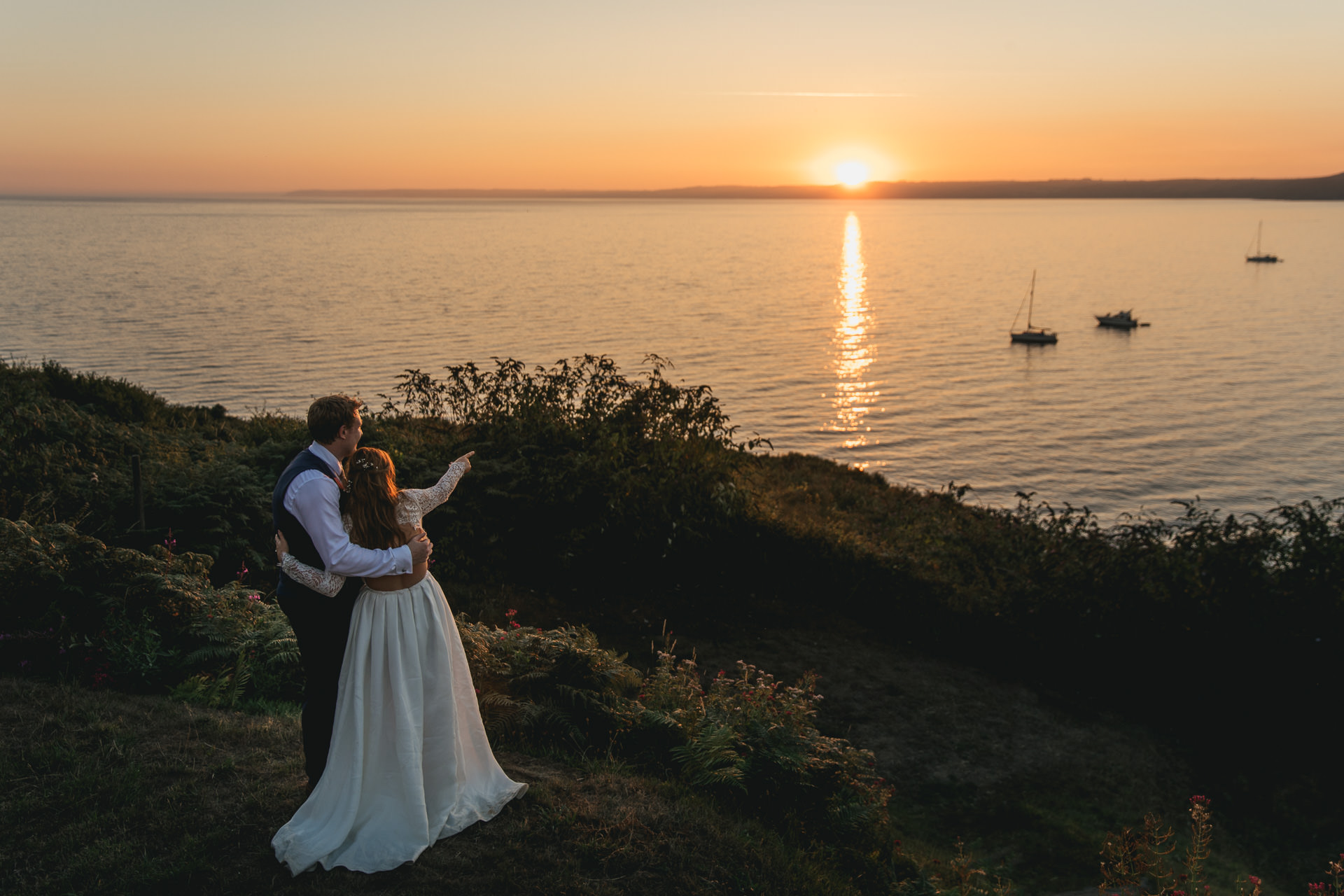 Bride and groom watching the sun set over the sea