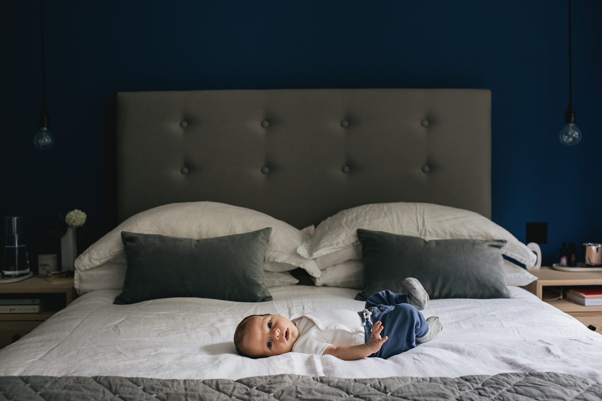 A baby lying on a bed during a newborn photography shoot at home