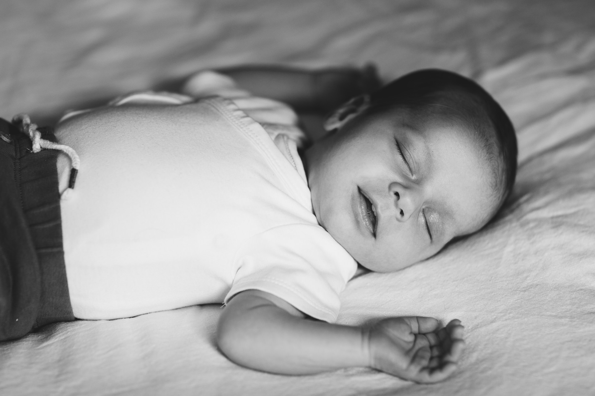 A baby boy sleeping and smiling during a newborn photography session at home