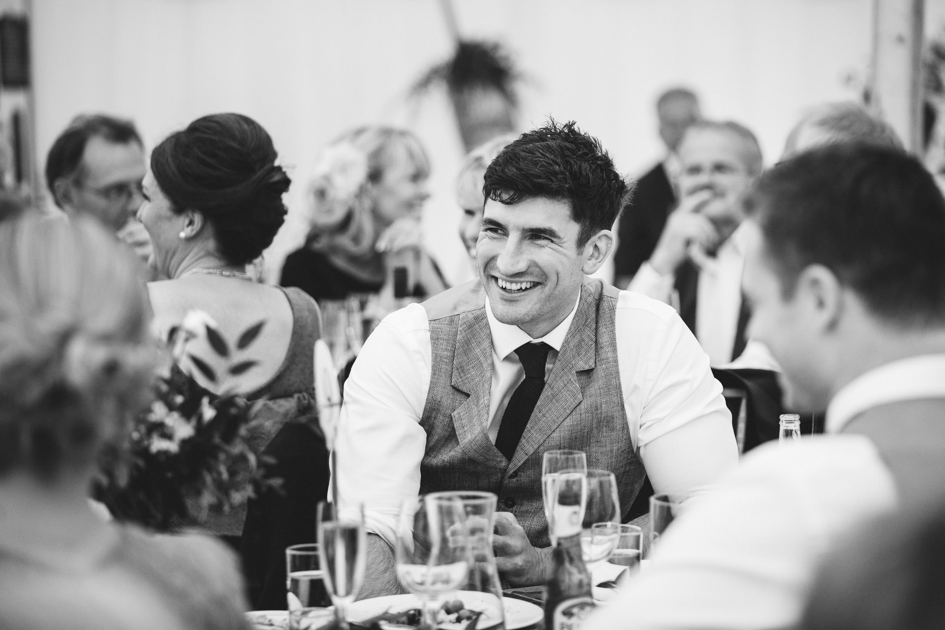 Guests laughing at wedding speeches inside a marquee