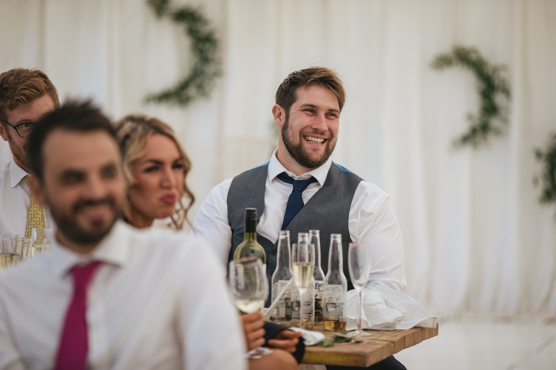 Guests laughing at wedding speeches inside a marquee