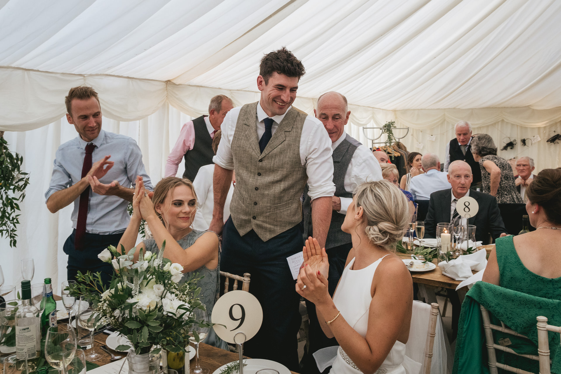 Groom laughing with bride in marquee