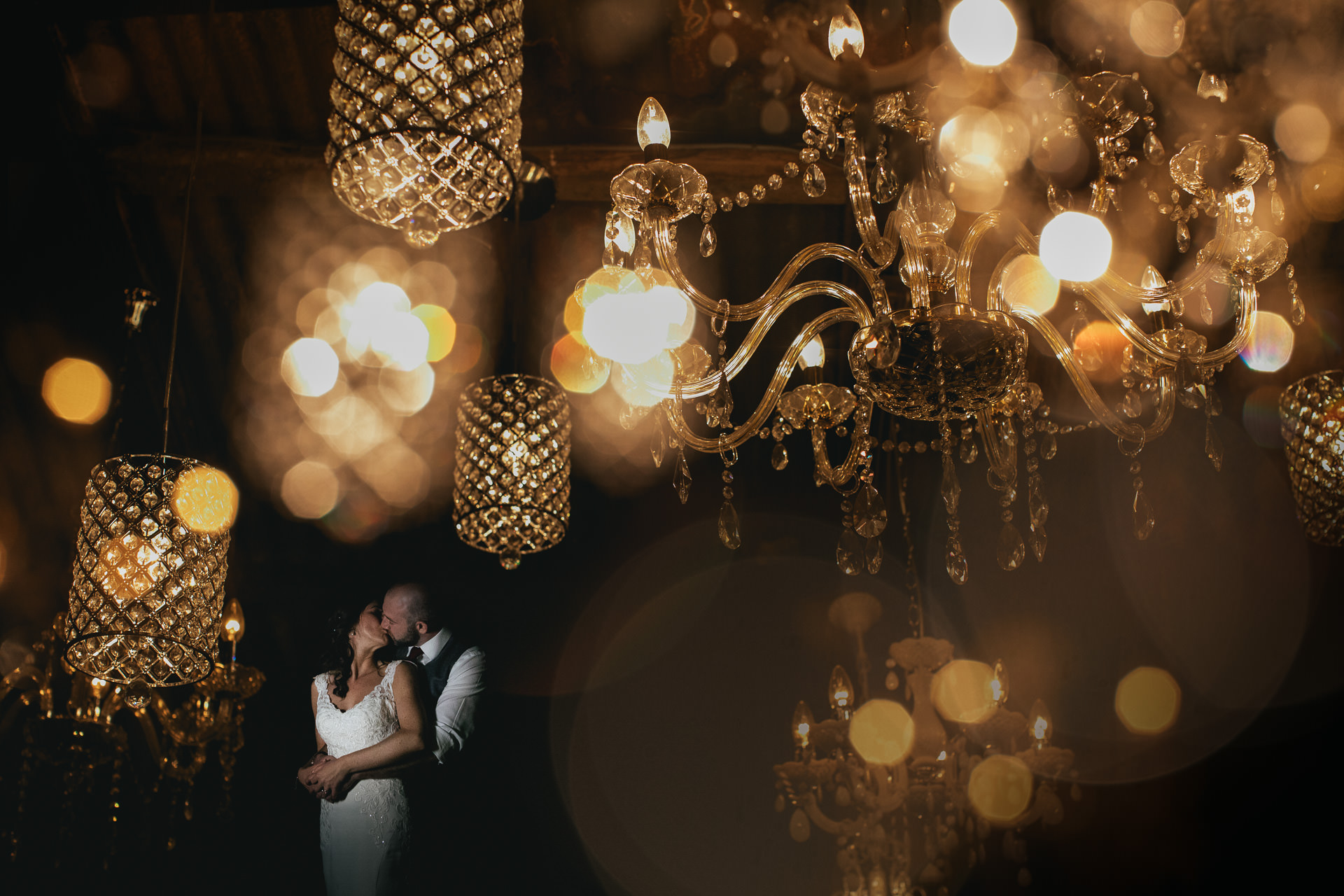Bride and groom surrounded by chandeliers