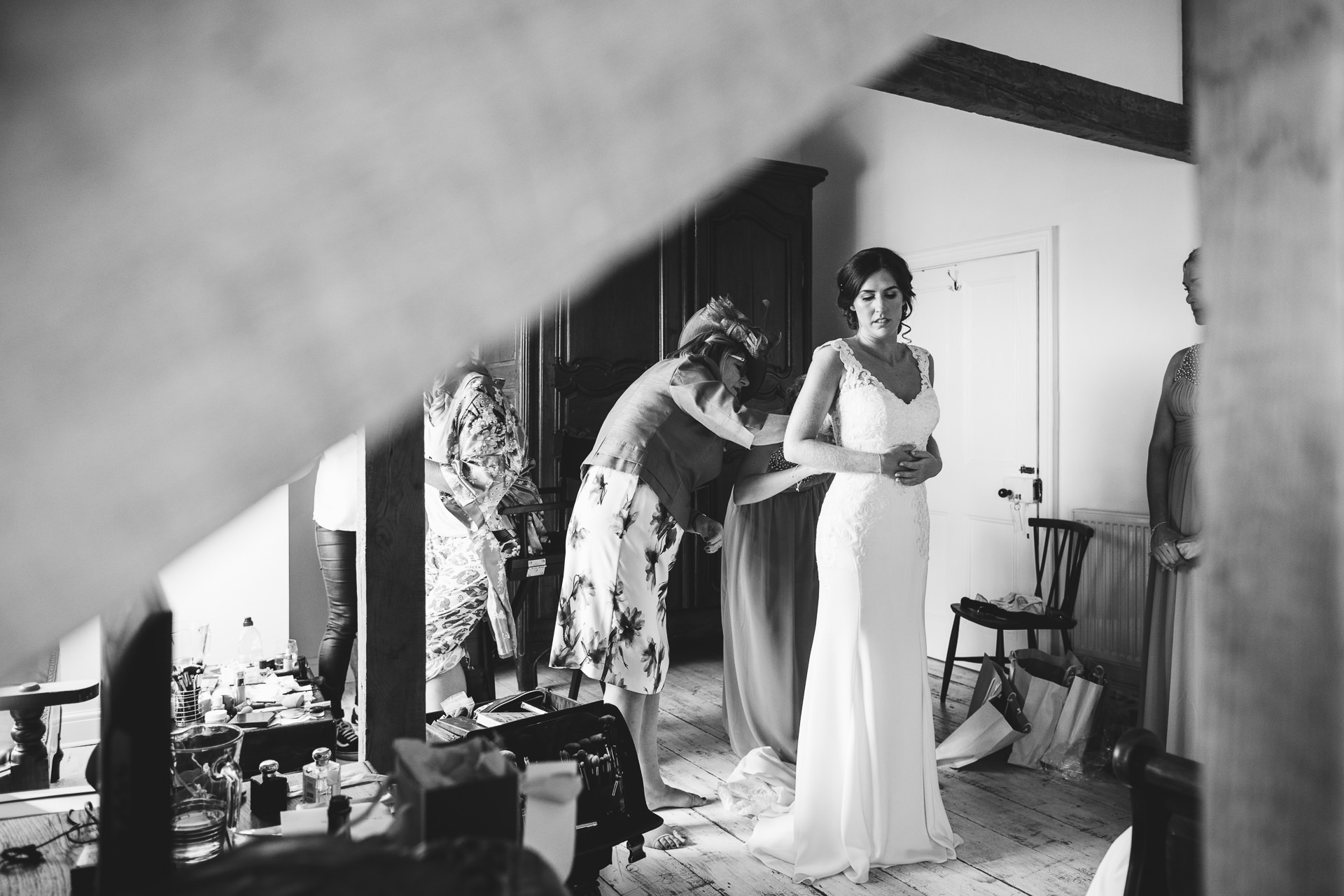 Bride's mother helping her put on her wedding dress