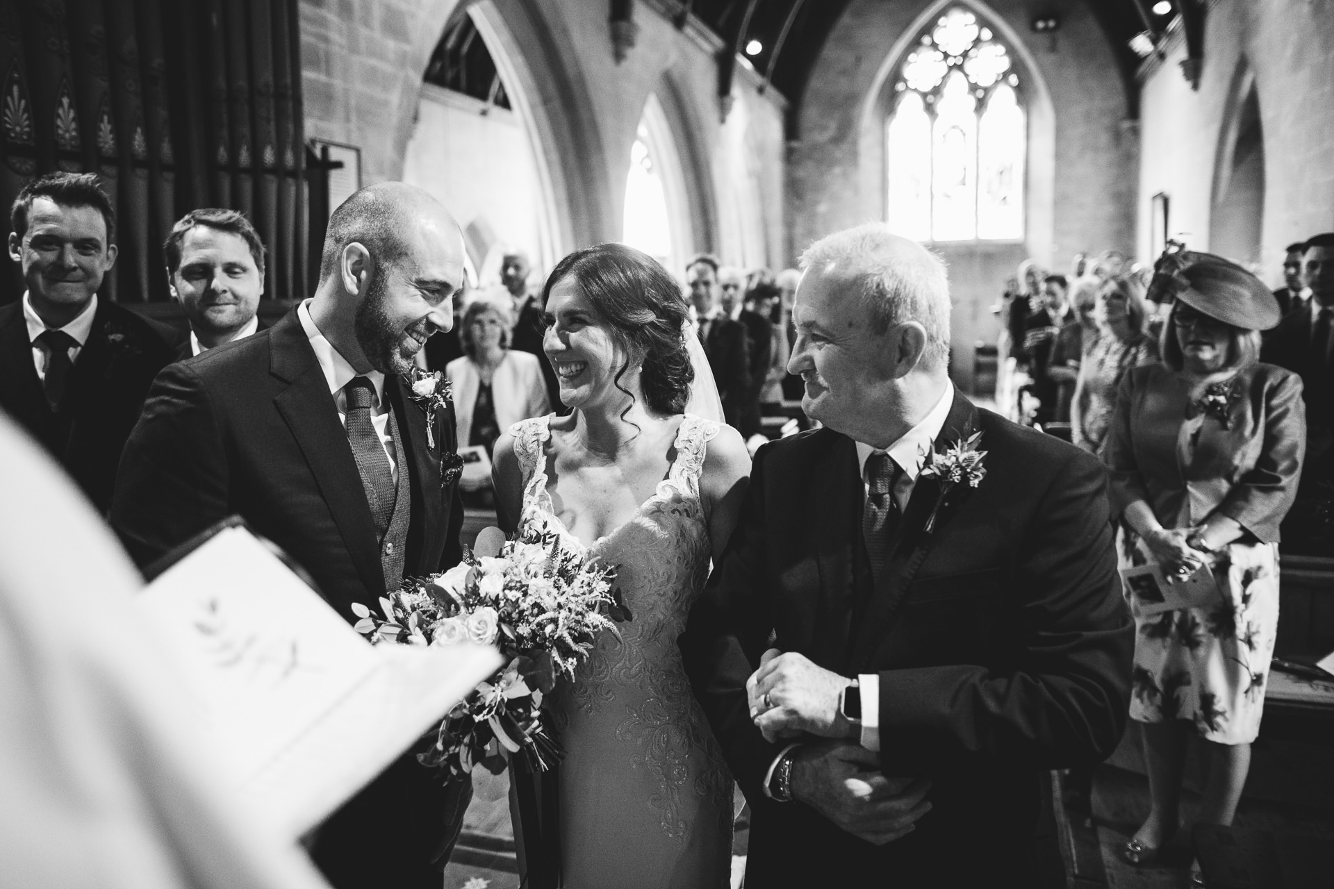 Bride and groom smiling at each other in church