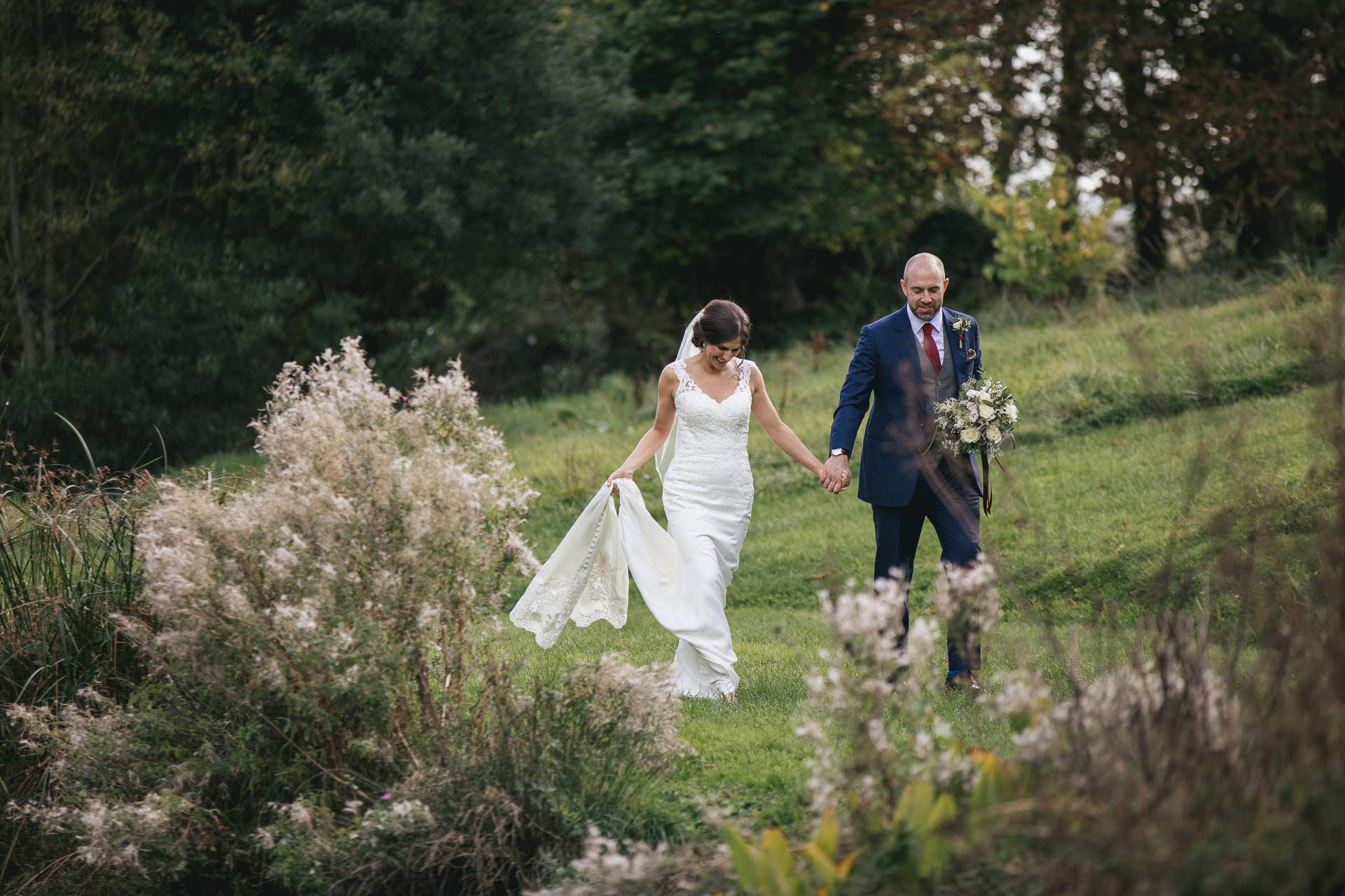 Bride and groom walking across Devon fields hand in hand