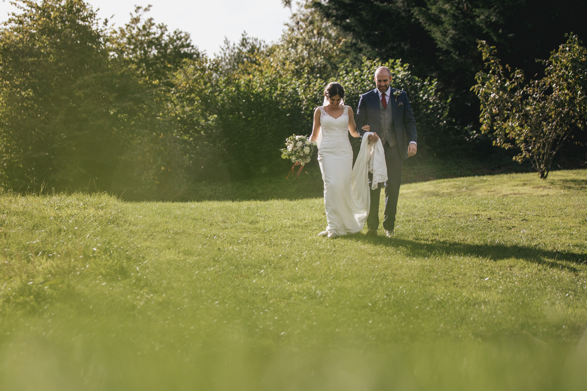 Bride and groom walking across the grass together