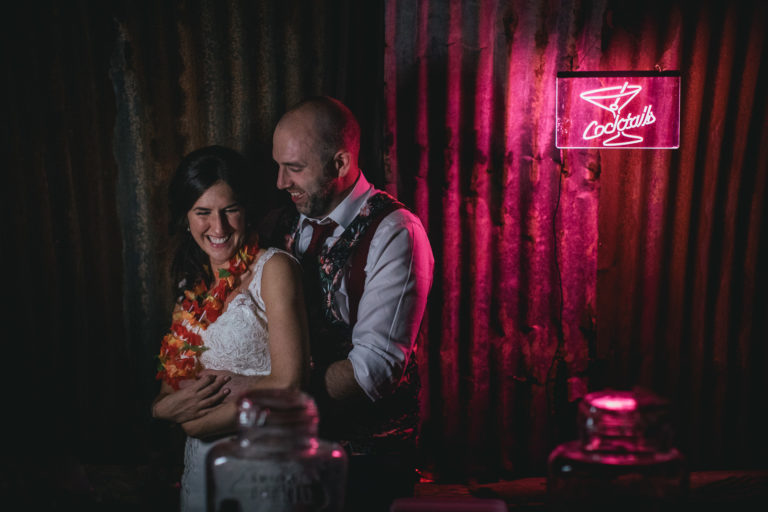Bride and groom next to neon pink cocktail sign