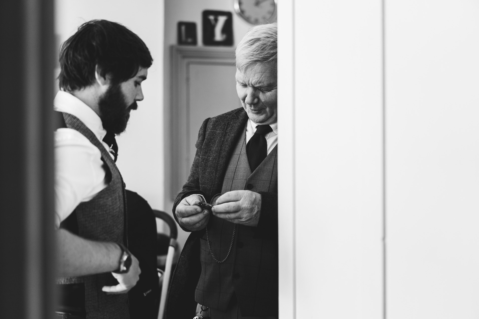 Groom and father looking at pocket watch