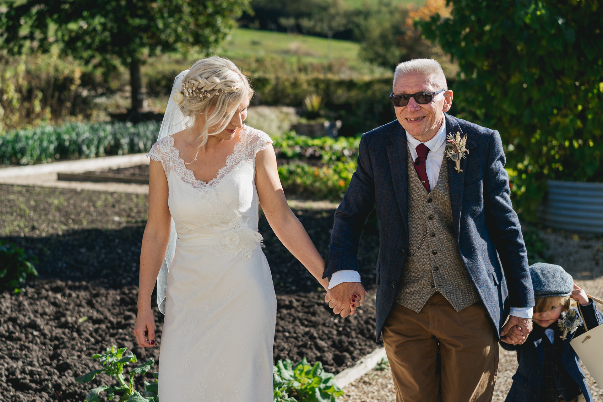 Bride hand in hand with her father walking through the garden